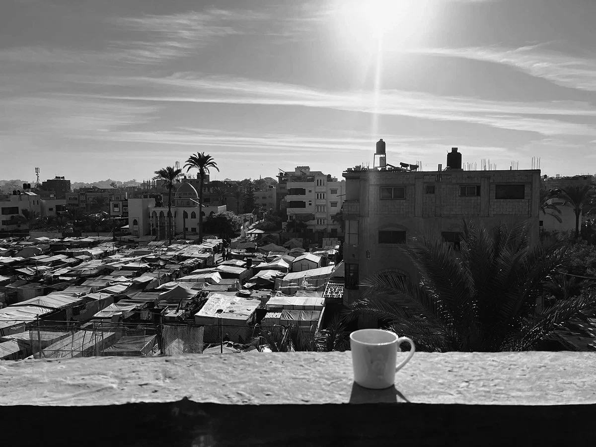 Panoramic view of a refugee camp and derelict buildings  with the sun on top,  black and white photo