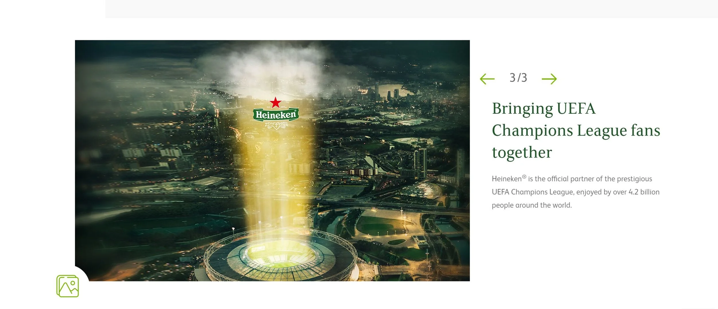 Aerial view of a city with a stadium underneath a promotional light. The Heineken logo is illuminated and positioned above the stadium.