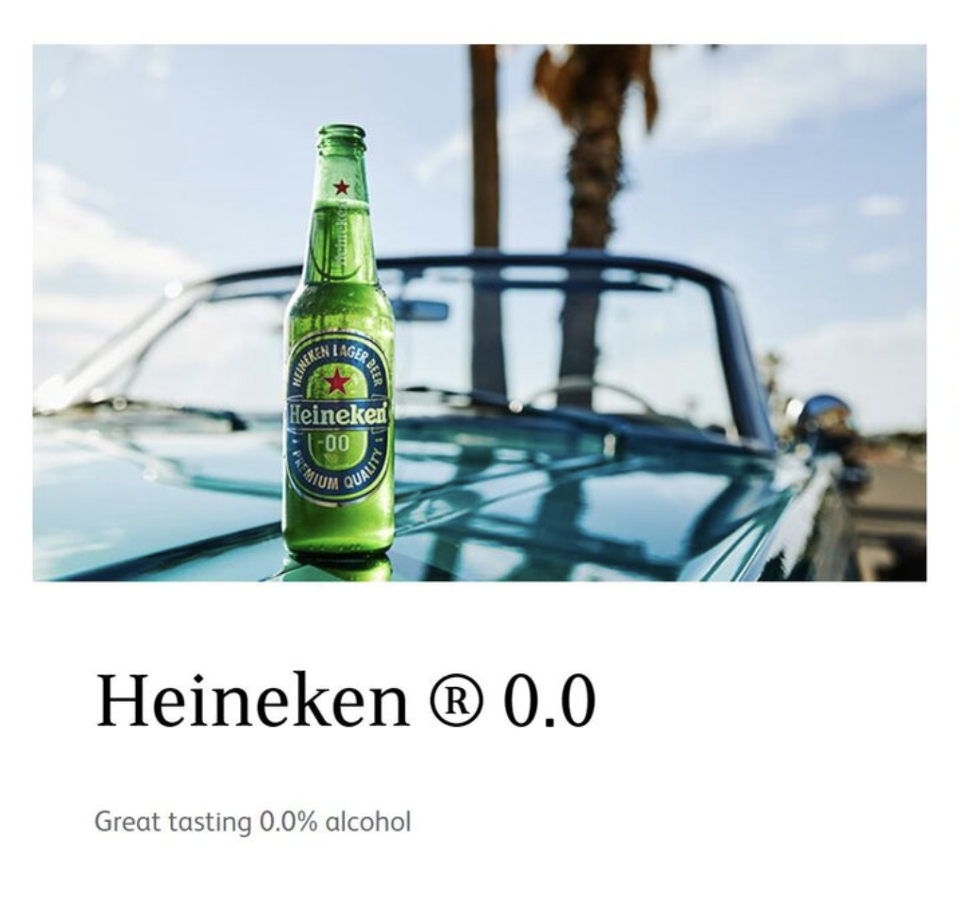 A green Heineken 0.0 bottle placed on the hood of a vintage car with palm trees and a blue sky in the background.