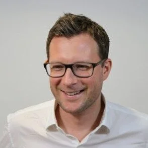 Person wearing glasses and a white shirt smiling