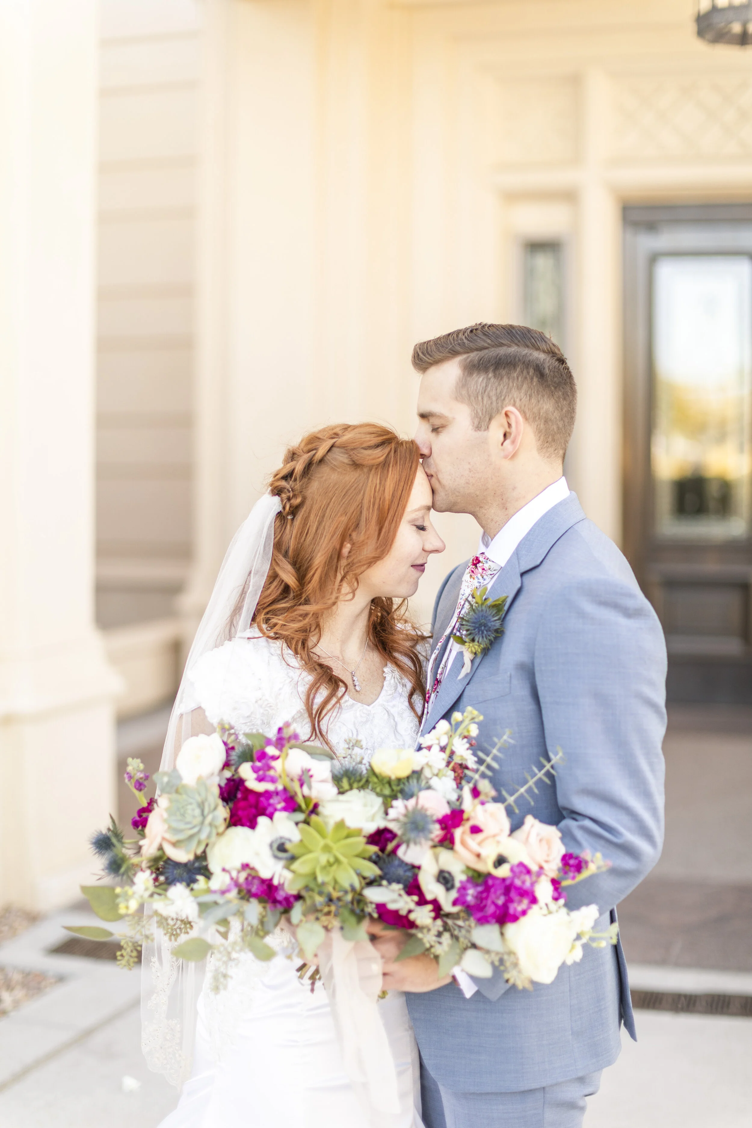  kissing on the forehead bridal wedding hairstyle inspiration how to wear your veil with your hair half up and half down beautiful unique bouquet colors and style inspiration beautiful bright and fun bouquet boutonniere inspiration man and wife pose 