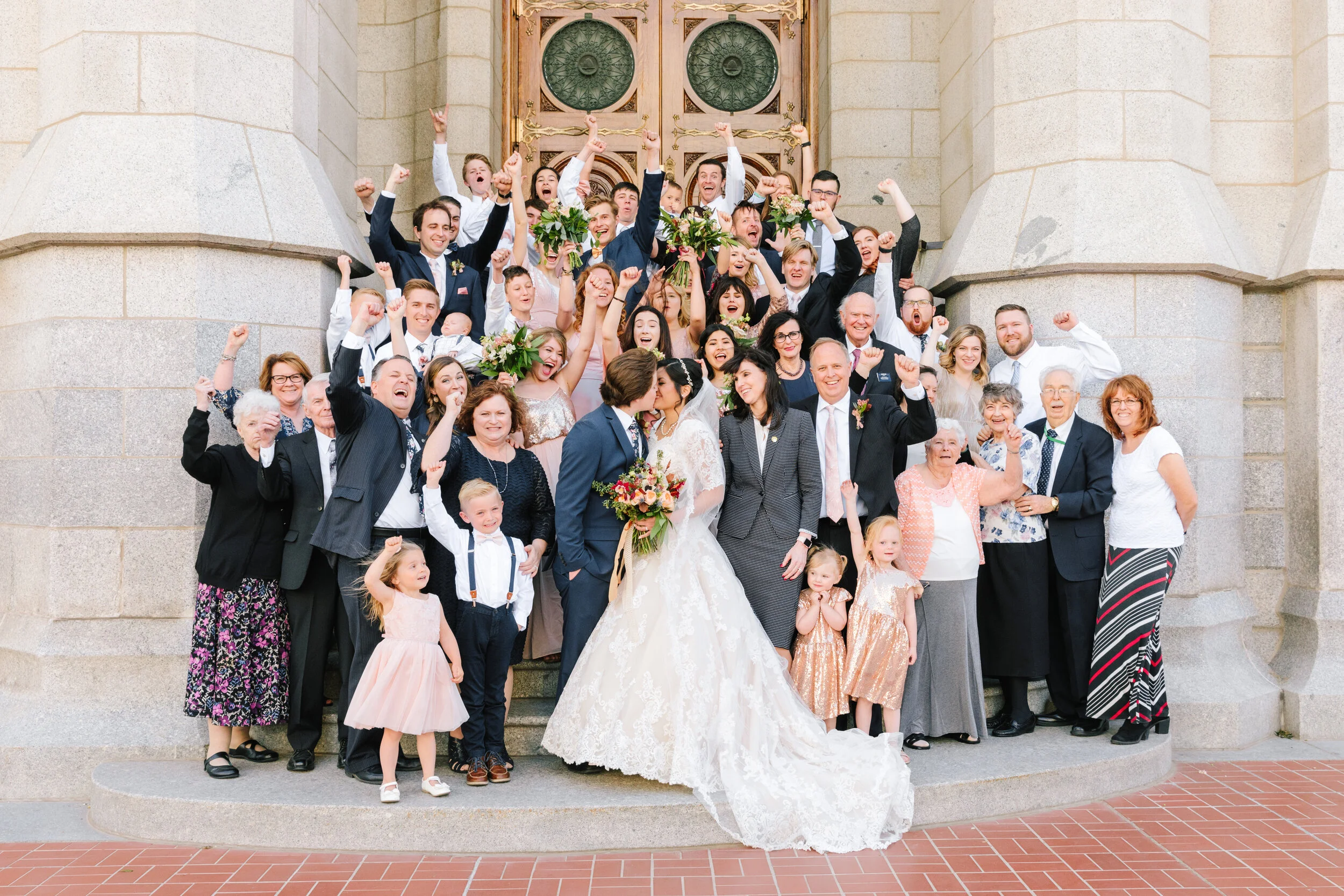  entire family on the temple steps celebrating the newly weds kissing couple pose inspiration family celebrates while couple kiss traditional lds wedding photo shoot traditional mormon wedding picture kiss on the temple steps families are forever lds