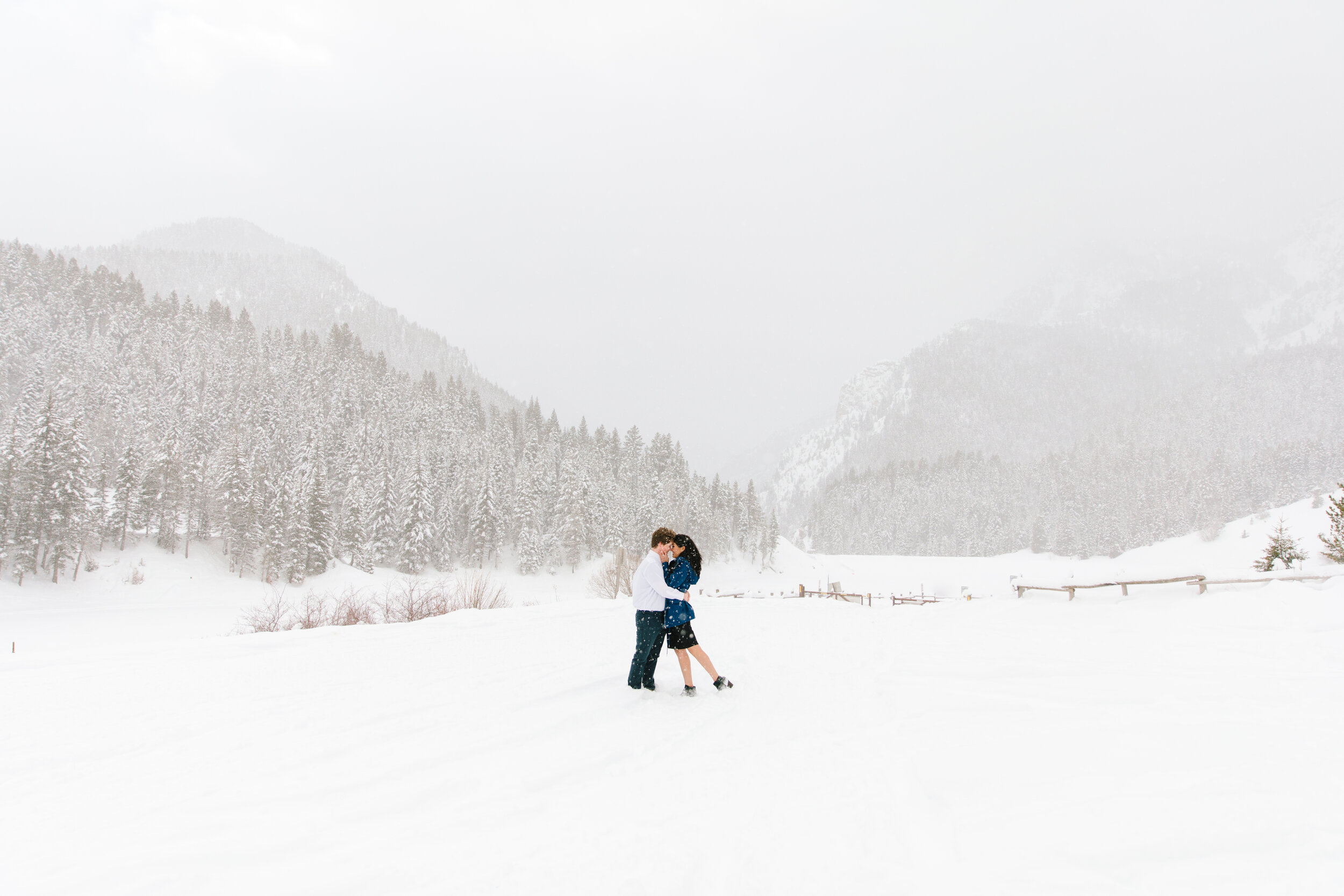  kissing in the snow beautiful mountain photo shoot session winter photo shoot goals foggy trees in the winter winter wonderland kissing in the distance couple pose inspiration couple goals winter photo shoot outfit inspiration winter goals winter en