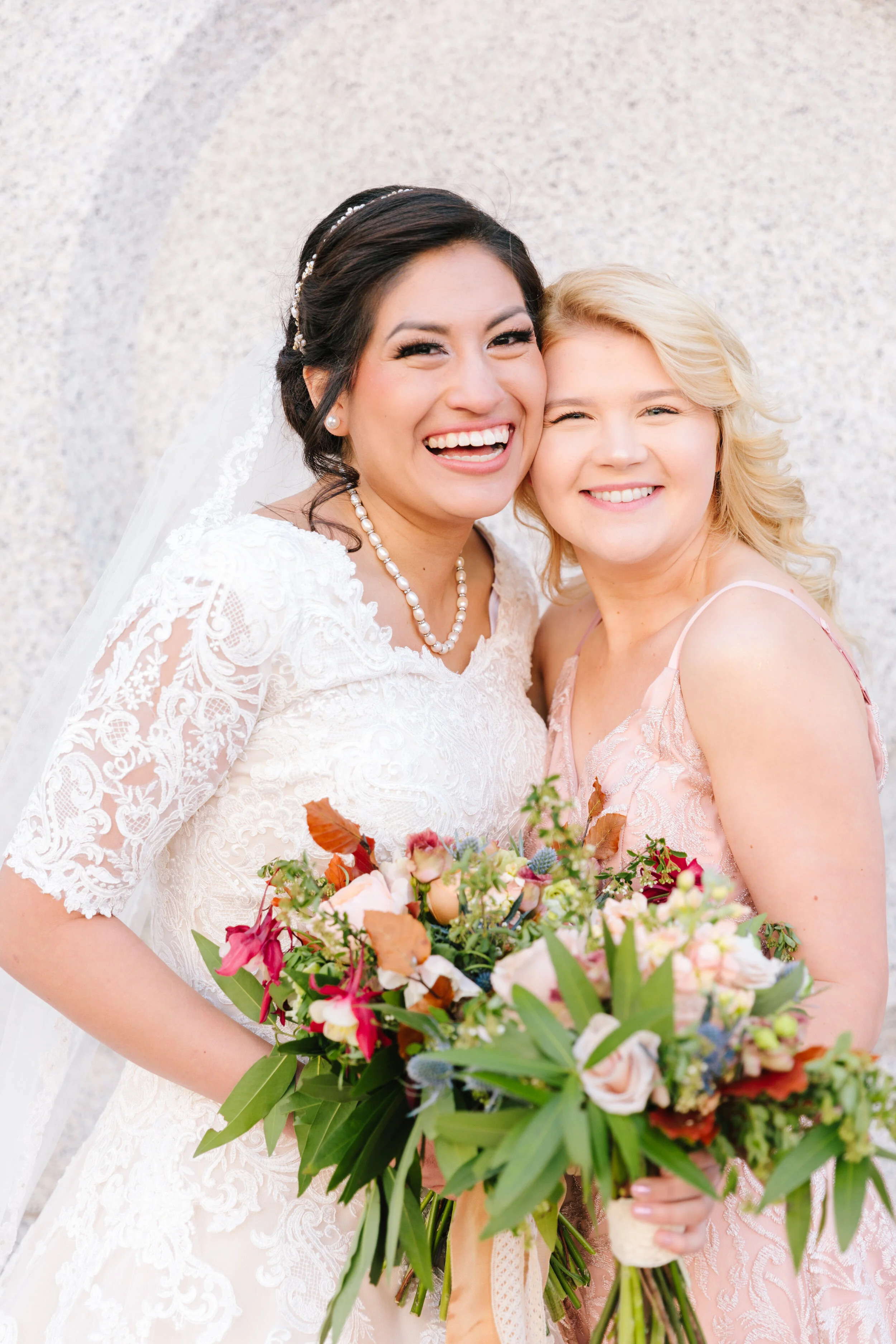  beautiful bride with her bridesmaid wedding bouquet inspiration wedding accessories inspiration beautiful bridal attire elbow length lace sleeves modest wedding dress inspiration modest lace wedding dress inspiration lds wedding dress inspiration we