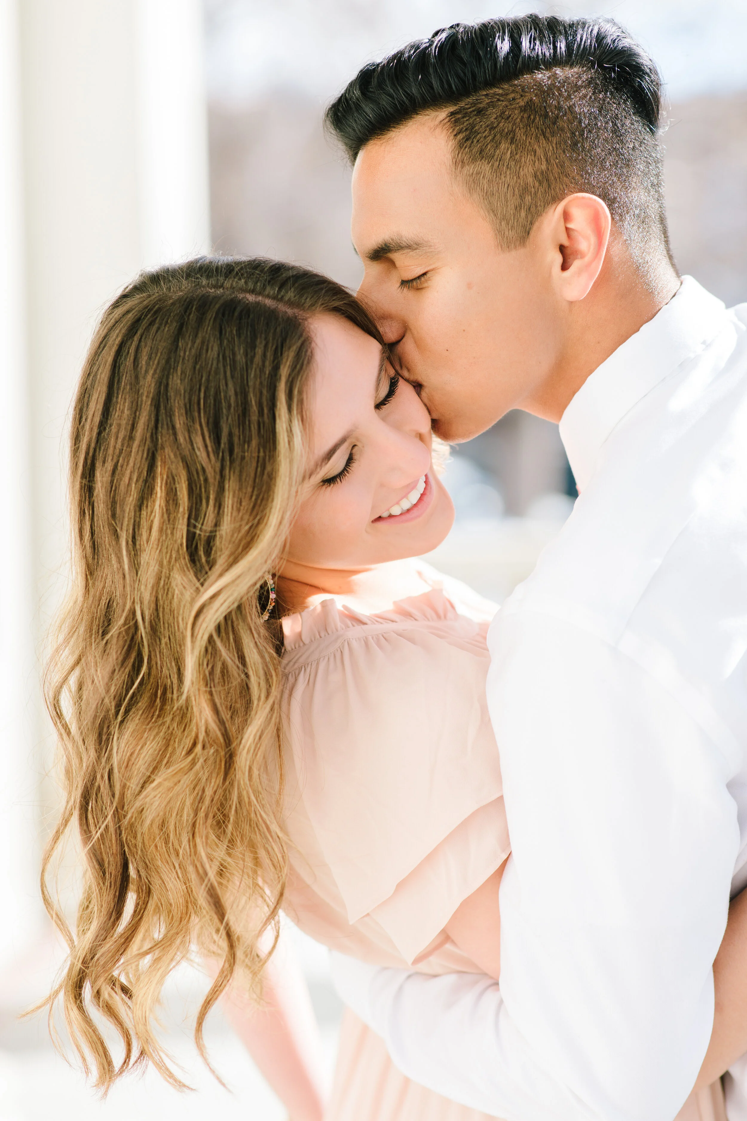  glowing soon to be man and wife unique kiss on the cheek pose inspiration unique couples pose inspiration beautiful movement soft curly hair inspiration couple outfit inspiration short sleeve soft pink engagement session ideas inspiration and goals 