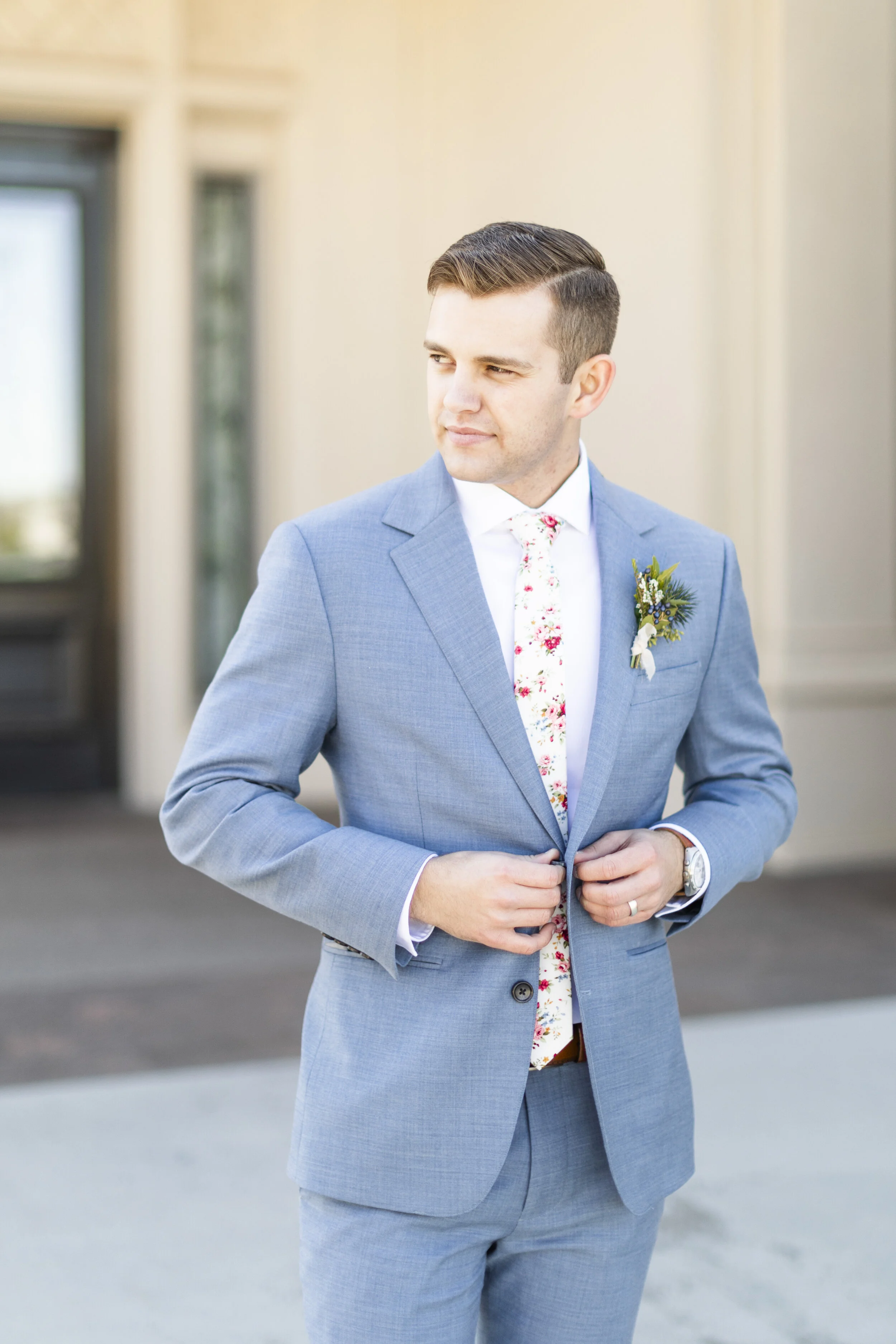  buttoning up the suit jacket groom wedding day photo shoot mens wedding hairstyle inspiration blue suit wedding attire inspiration for the groom floral tie white floral tie wedding floral tie inspiration groom wedding day attire lds wedding inspirat