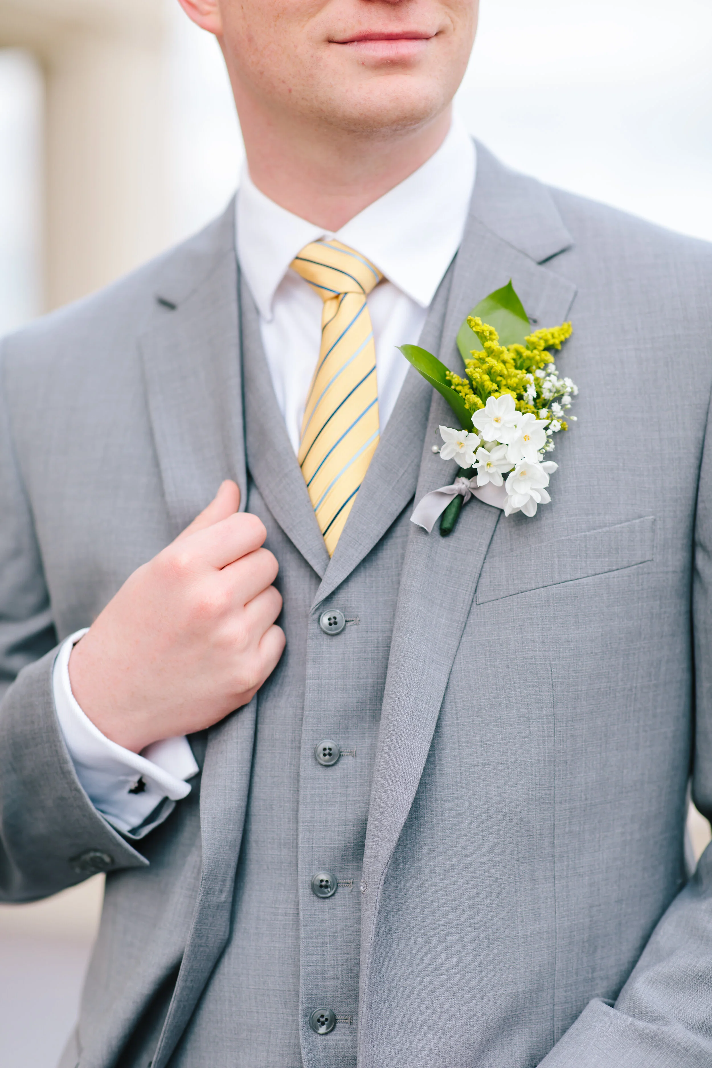  close up groom pose inspiration summer photo shoot spring photo shoot boutonniere inspiration yellow stripped tie wedding color tied in wedding attire for the groom three piece suit wedding suit inspiration grey wedding suit and tux groom pose #wedd
