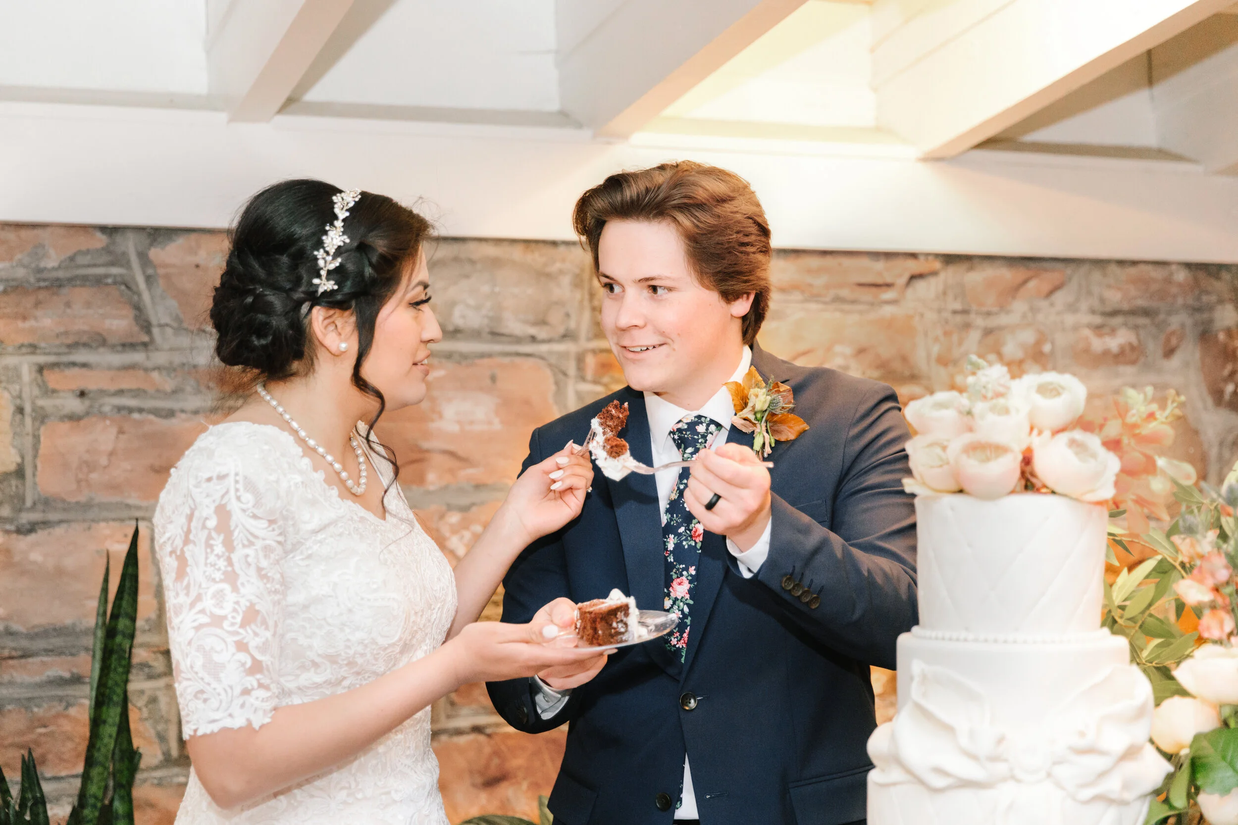  feeding each other the wedding cake roses on top of the wedding cake wedding reception attire for the bride and groom wedding cake inspiration beautiful wedding bow on the wedding cake sweet traditional moment wedding reception area goals inspiratio