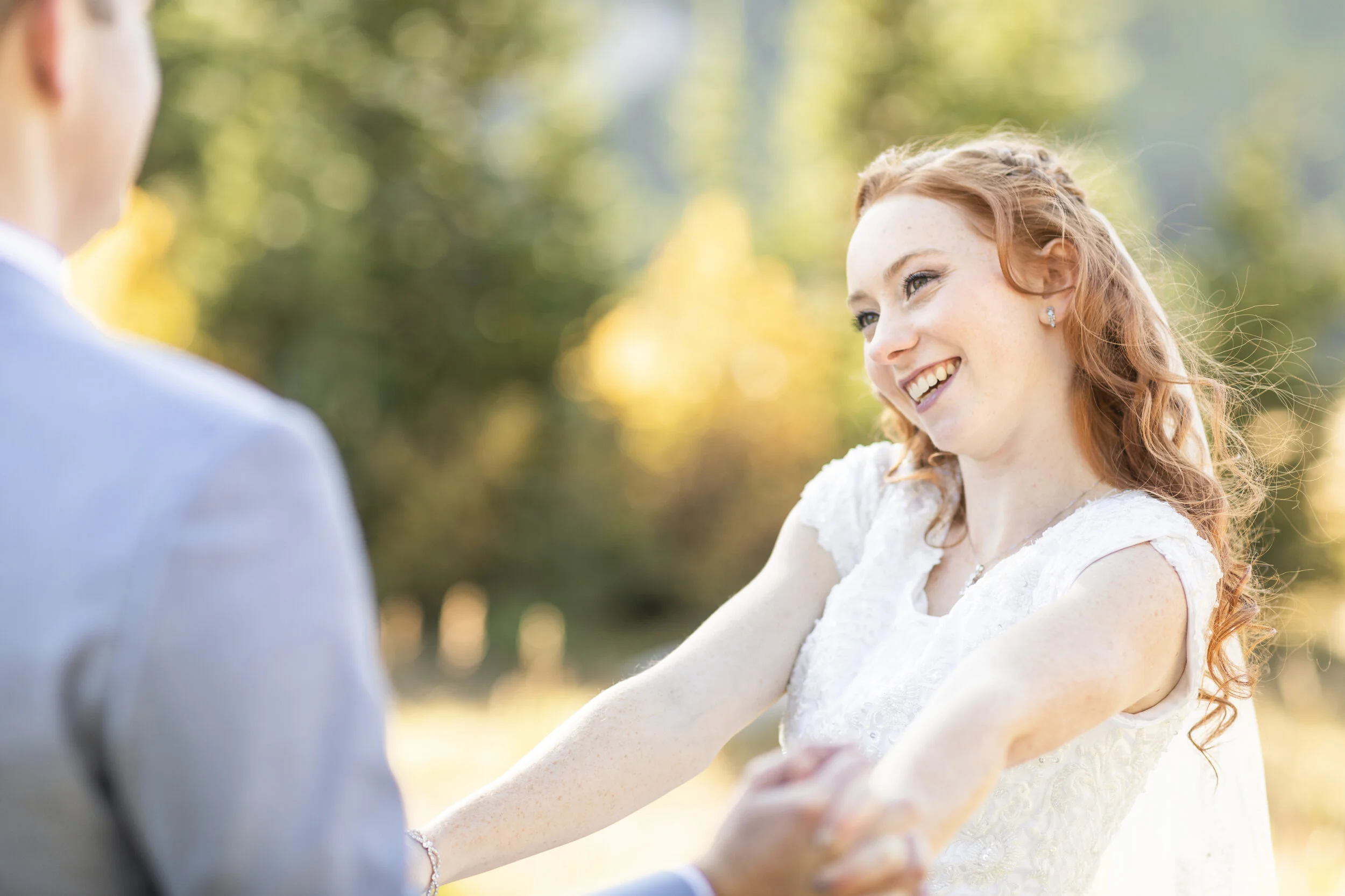  Beautiful bride smiling at her new husband first look photograph red haired bride authentic smile capturing the moment bride in focus true to color photography big cottonwood canyon bridals holding hands outdoor wedding inspiration happy couple salt