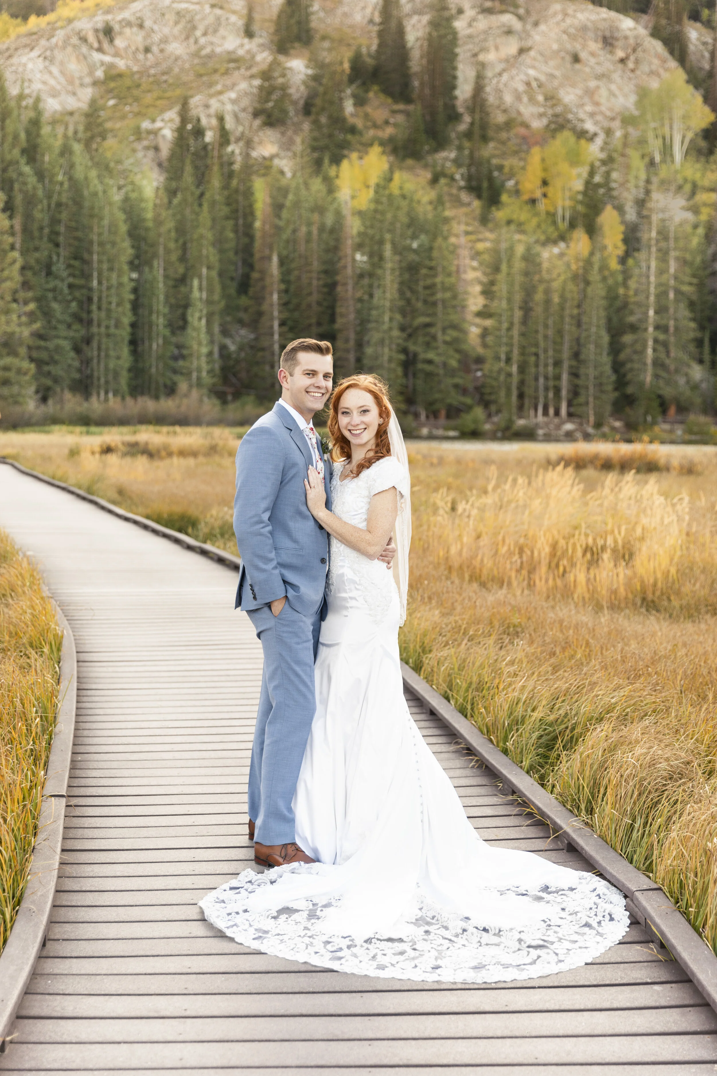  Bride and groom standing on path in big cottonwood canyon silver lake salt lake city utah full body portrait gorgeous lace train wedding gown homemade wedding dress steel blue suit groomsmen outfits groom attire red hair wedding hairstyle fall grass