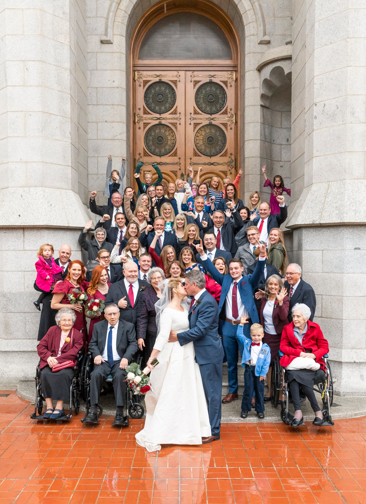  temple exit salt lake city lds temple temple square large group photo celebrating hands in the air bride and groom kissing happy rainy wedding day cranberry red and navy wedding colors professional salt lake city wedding photographer #saltlakeldstem
