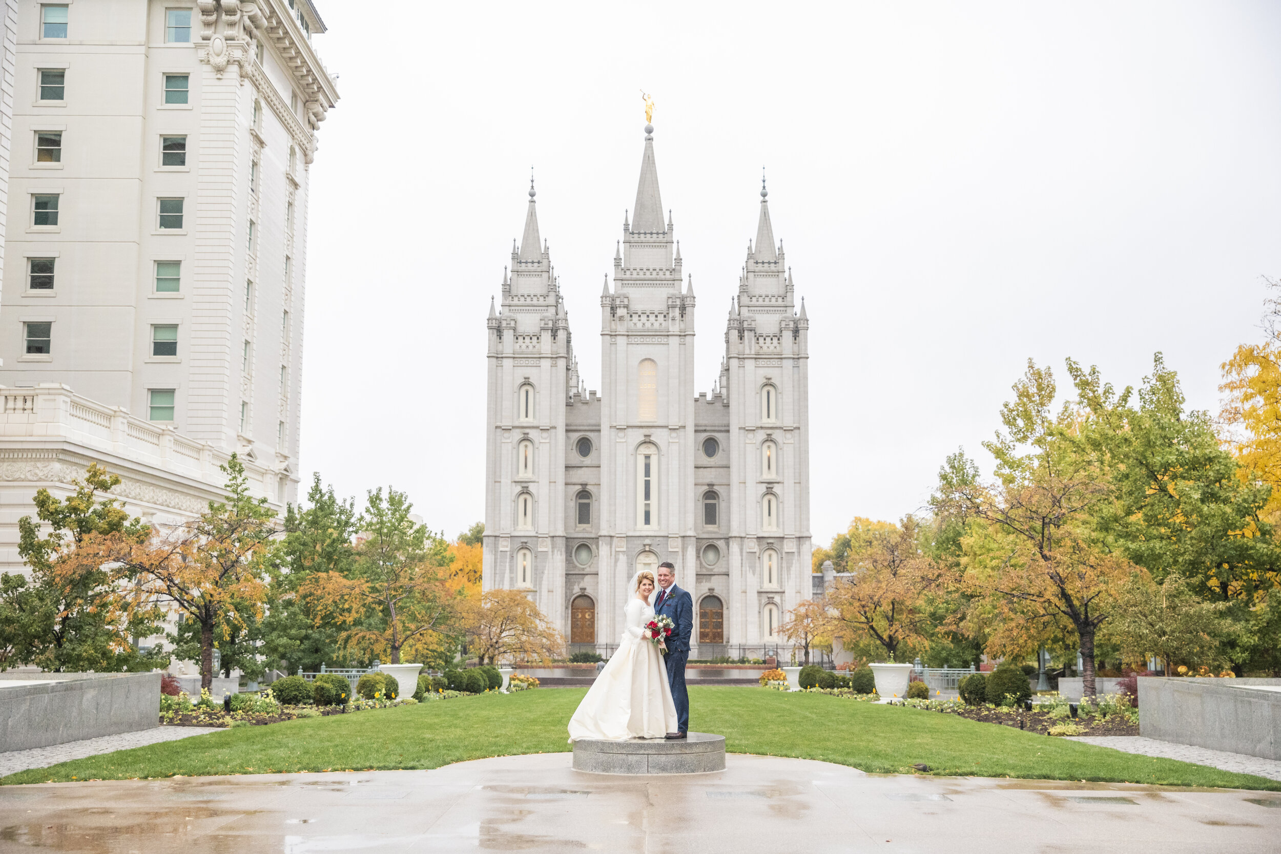  temple square salt lake city lds temple holiness to the lord yellow fall trees rainy wedding day just married sealed full ballgown modest wedding dress holding hands hugging smiling professional utah valley wedding photographer #saltlakeldstemple #s