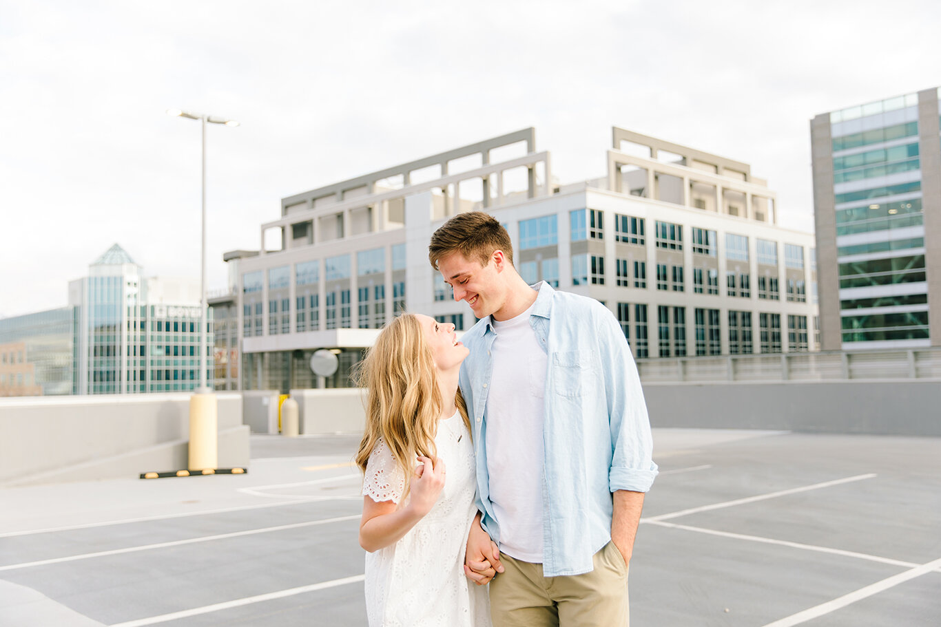  side by side loose hanging curls light blue collared casual shirt white lace short sleeve dress downtown city buildings cityscape city creek mall harmon’s building salt lake city utah professional utah valley engagement photographer #downtownsaltlak