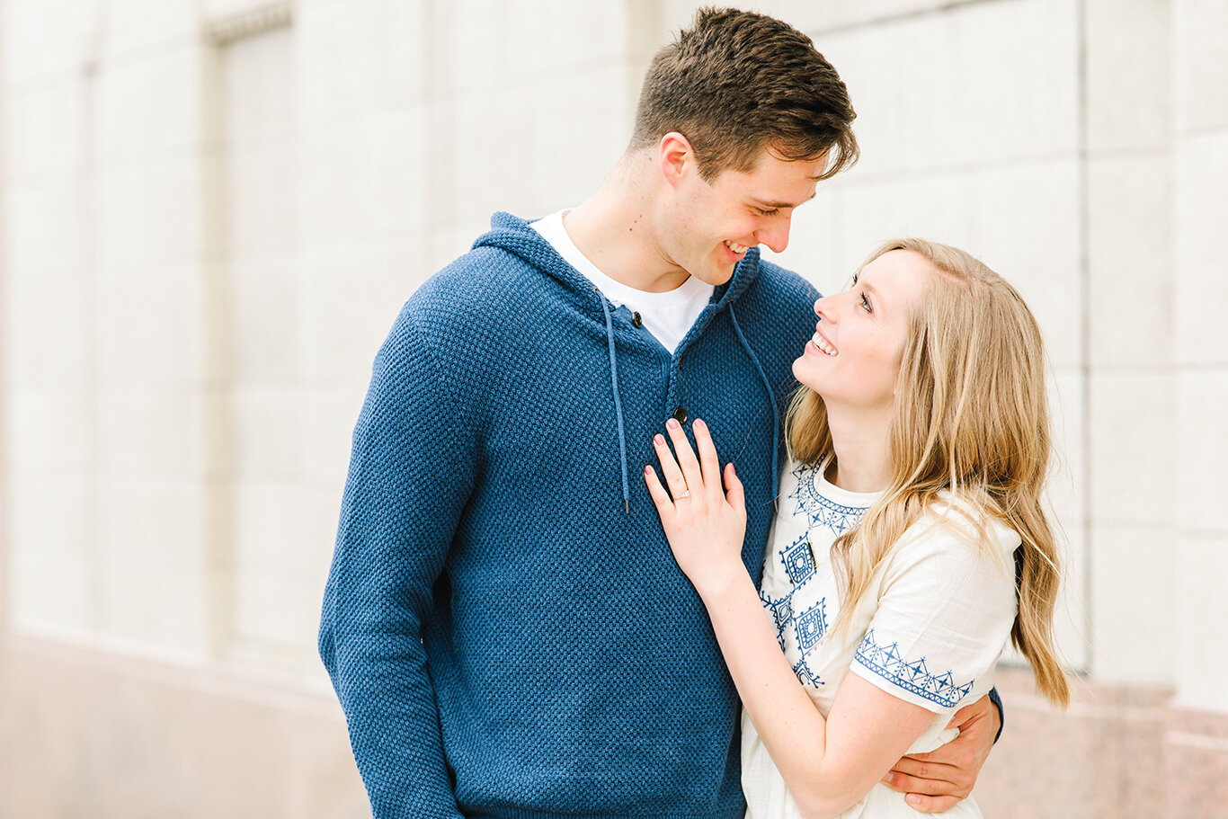  navy blue pullover sweater navy accent solitaire diamond engagement ring loose hanging curls smiles gazing into each others eyes close up photo downtown engagement photo session  salt lake city utah professional utah valley engagement photographer #