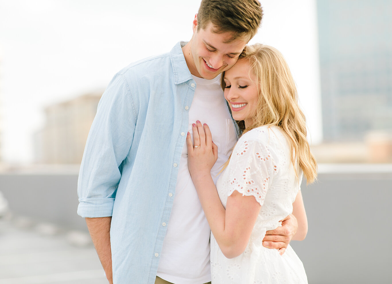  light blue collared shirt white lace dress engagement ring display smiling roof top engagement session downtown salt lake city utah salt lake city utah professional utah valley engagement photographer #downtownsaltlakecity #engagements #utah #saltla