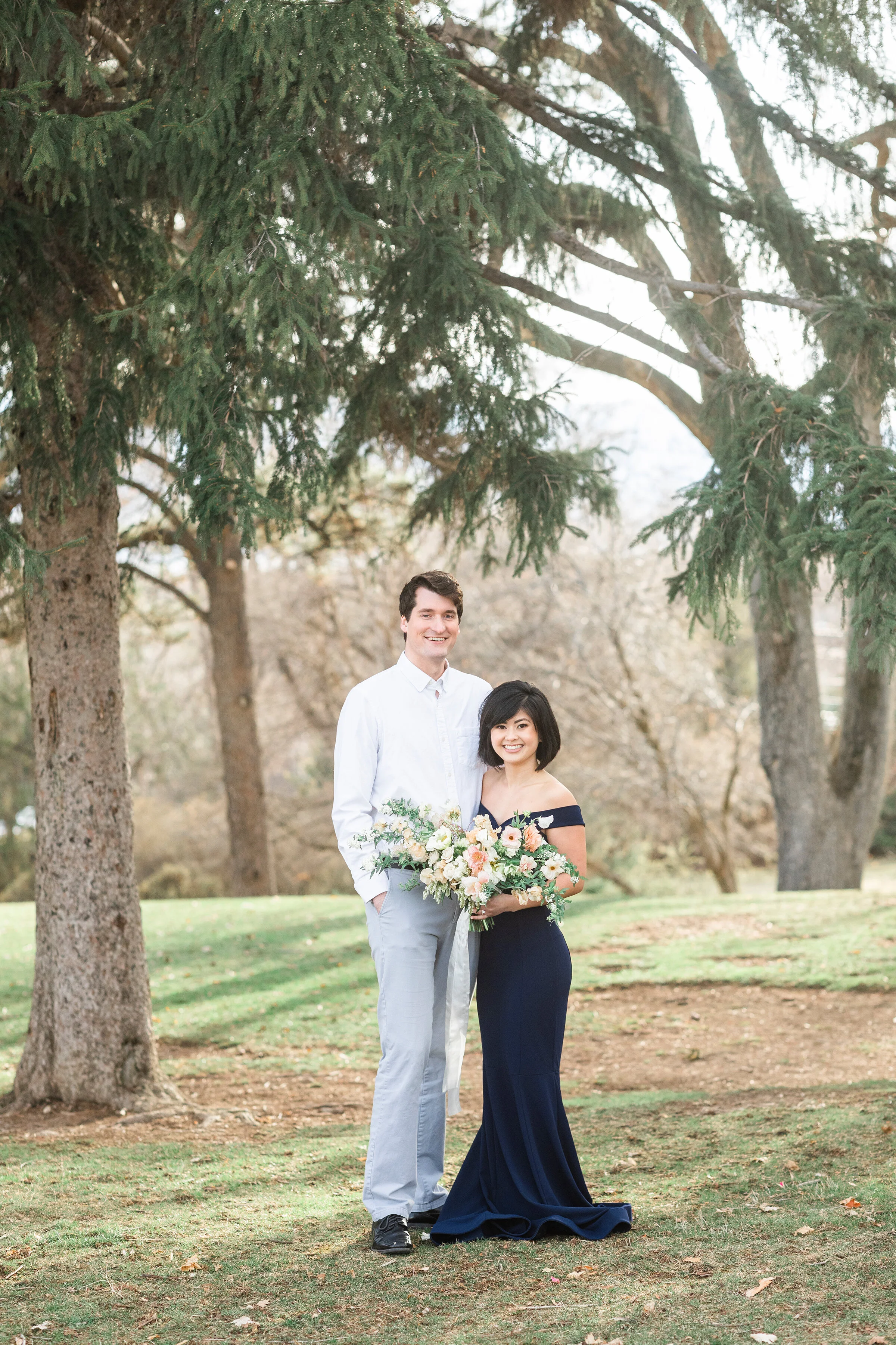  A beautiful newly wed couple standing together in the early morning mist of a dark winters day in a formal photo shoot. Photo shoot inspiration ideas and goals off the shoulder mermaid dress inspiration romantic dress inspiration unique bouquet insp