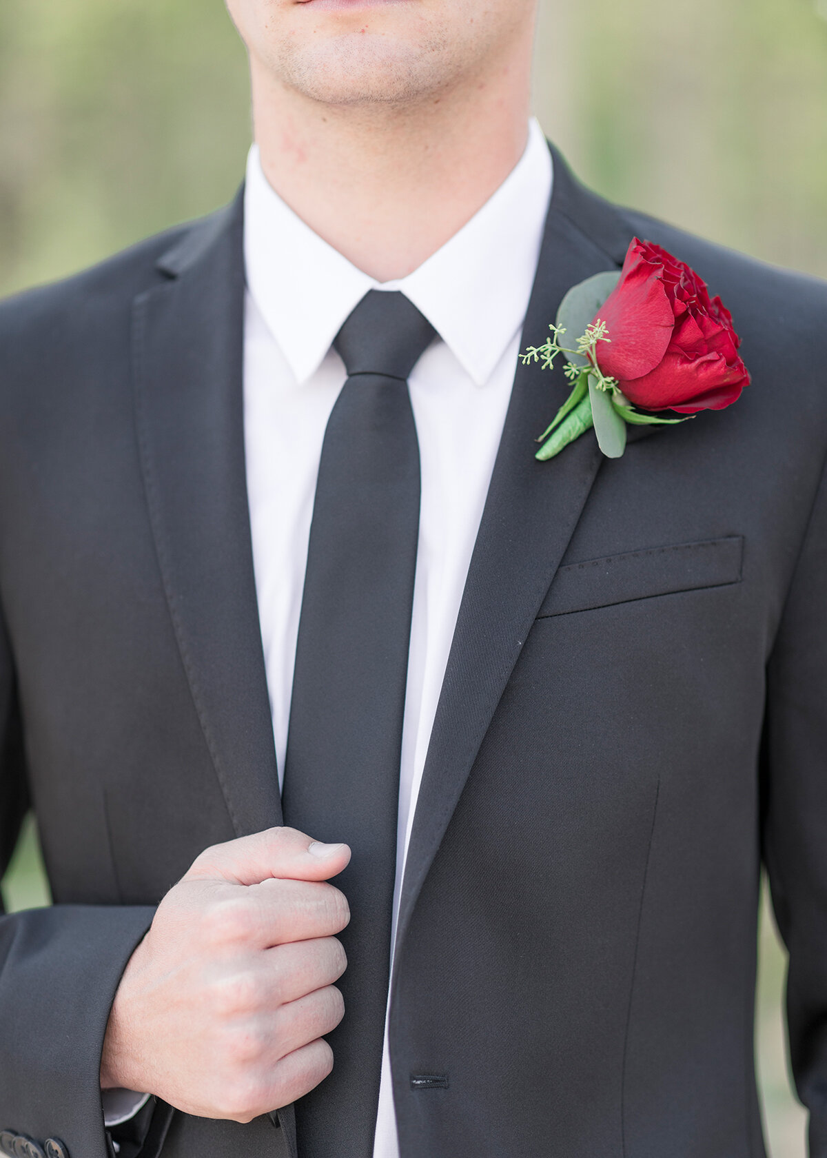  Detail shot of grooms dark gray suit with dark gray tie and single rose boutonniere in Salt Lake City, Utah by Clarity Lane Photography. grooms wedding outfit inspo how to dress your groom simple suits for grooms gray suit for groom roses for weddin