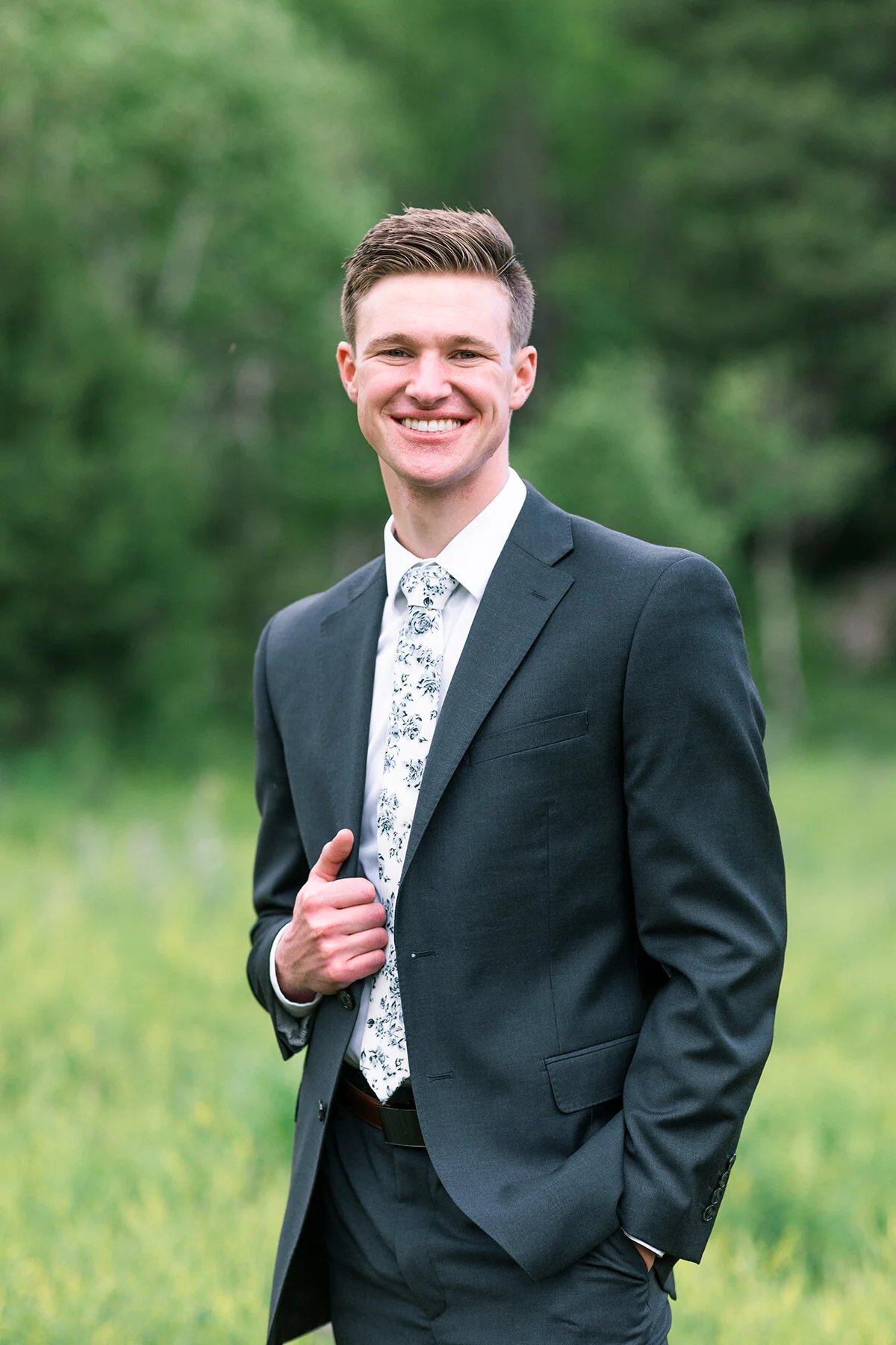  Happy groom with white and black floral tie and black suit in this close up shot by Clarity Lane Photography in Northern Utah. black and white wedding colors black suit for groom how to dress your groom wedding outfit inspo for grooms fun wedding ti
