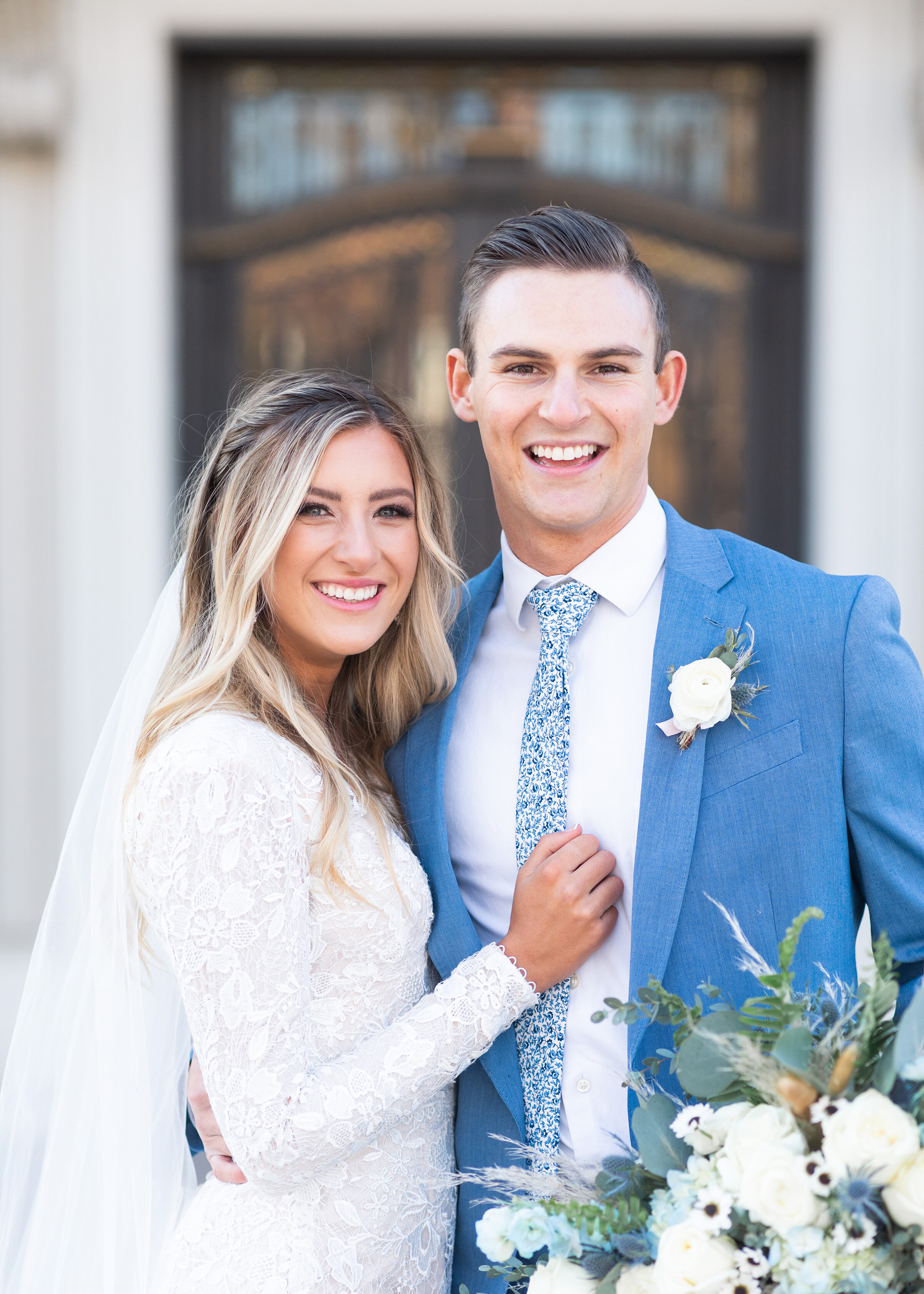  Clarity Lane Photography shoots these happy newlyweds at their reception venue in Salt Lake City, Utah. blonde balyage bridal hair, loose curled bridal hair, half braid bridal hair, long romantic bridal veil, blue wedding suit, blue and white weddin