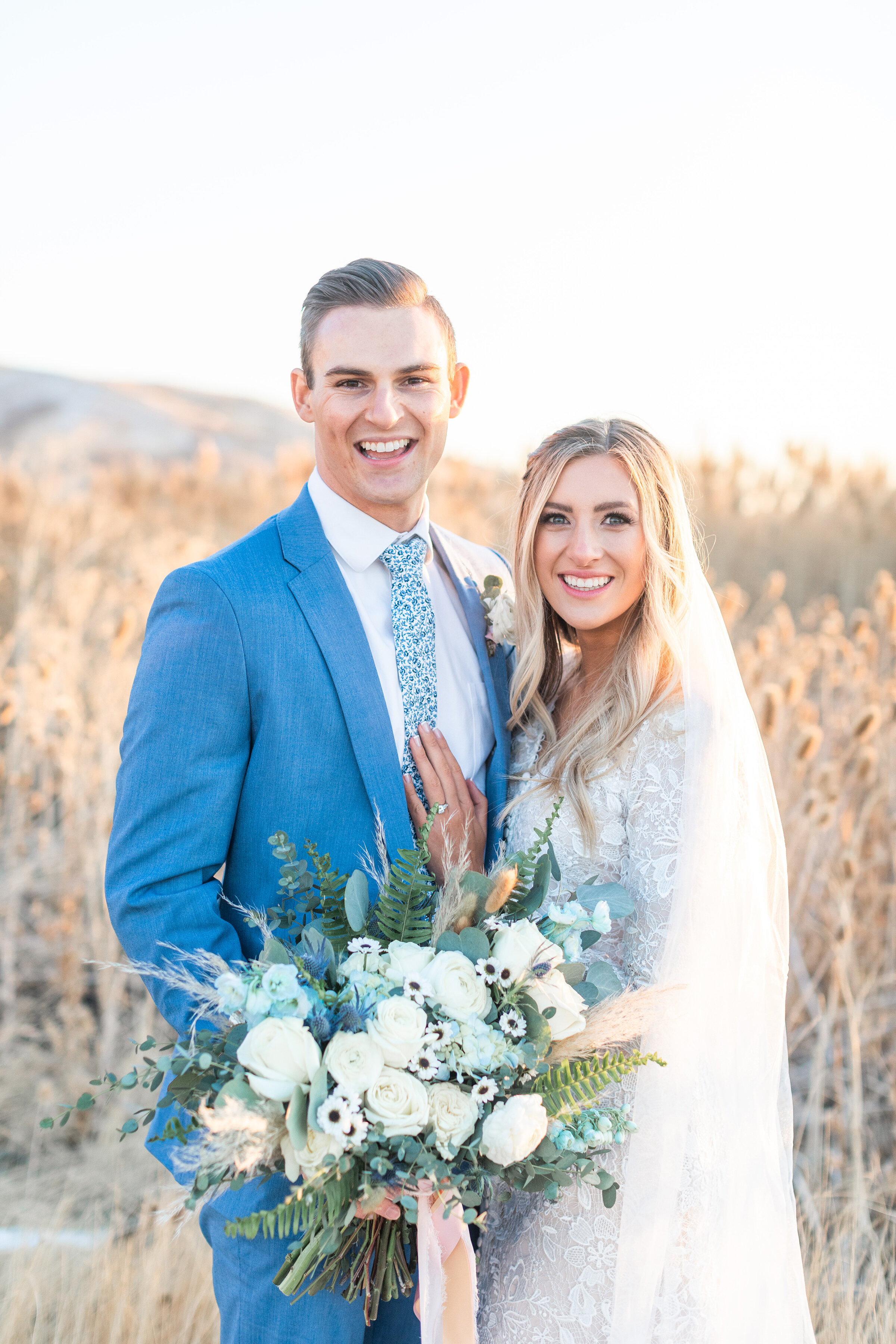  Clarity Lane Photography captures an in-love bride and groom pose amongst tall grass in an open field in Salt Lake City, Utah. tunnel springs park bridal photos, tall grass and rolling field utah bridal session, clarity lane photography photography,