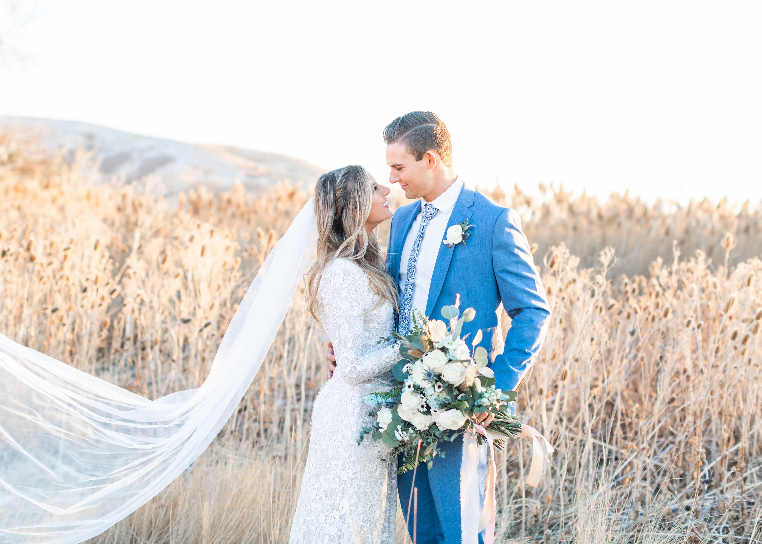 Set amid rolling Utah hills and tall dried grass, Clarity Lane Photography captures a love-filled wedding session in Tunnel Springs Park in Salt Lake City, Utah. professional bridal session photographer in salt lake city utah, long bridal veil train