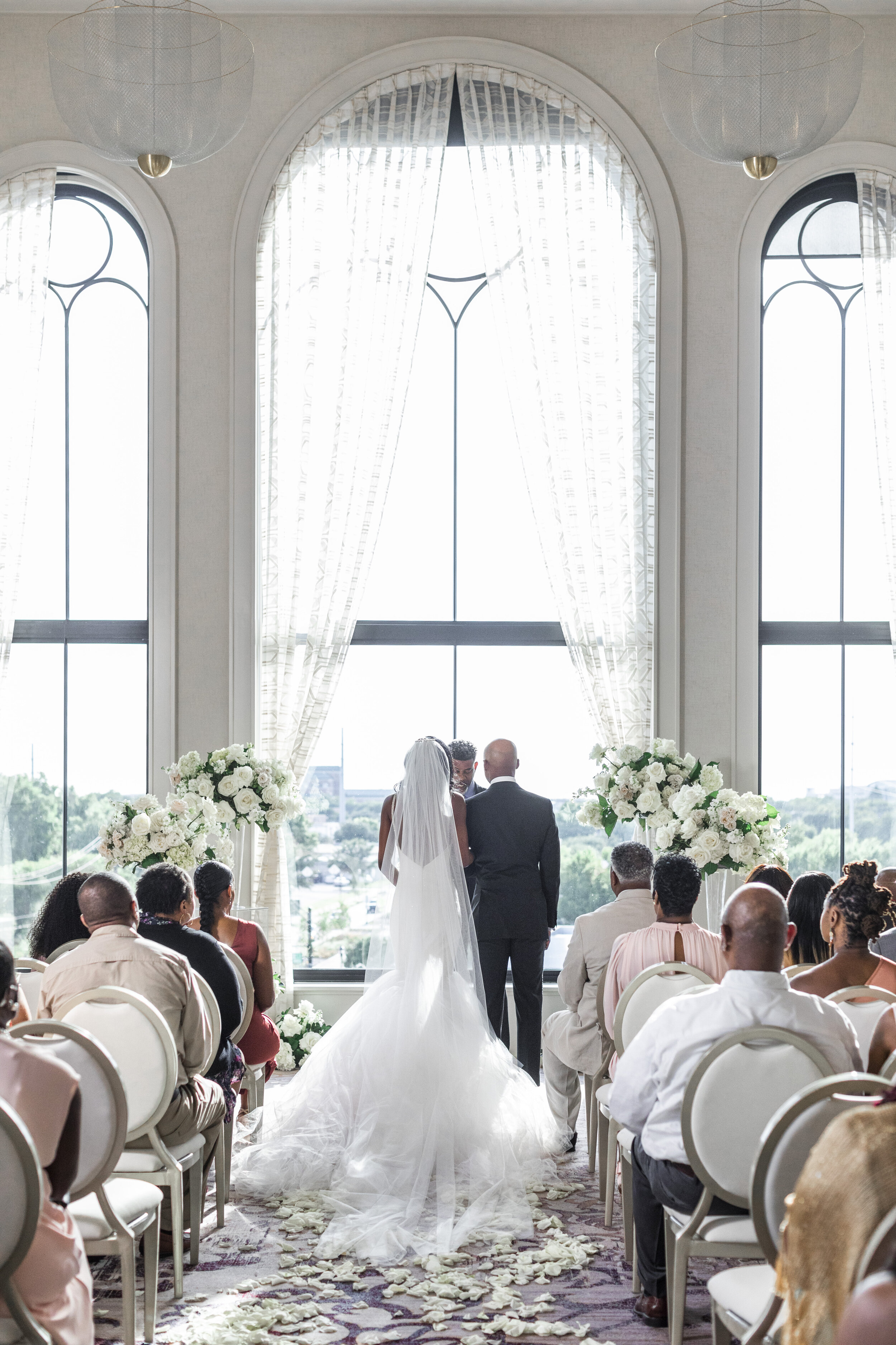  A bride and groom stand at the alter in an elegant indoor wedding venue in Texas. Natural light photography dallas texas wedding venue high end wedding photography wedding dress inspiration white wedding flowers bride and groom wedding ceremony idea