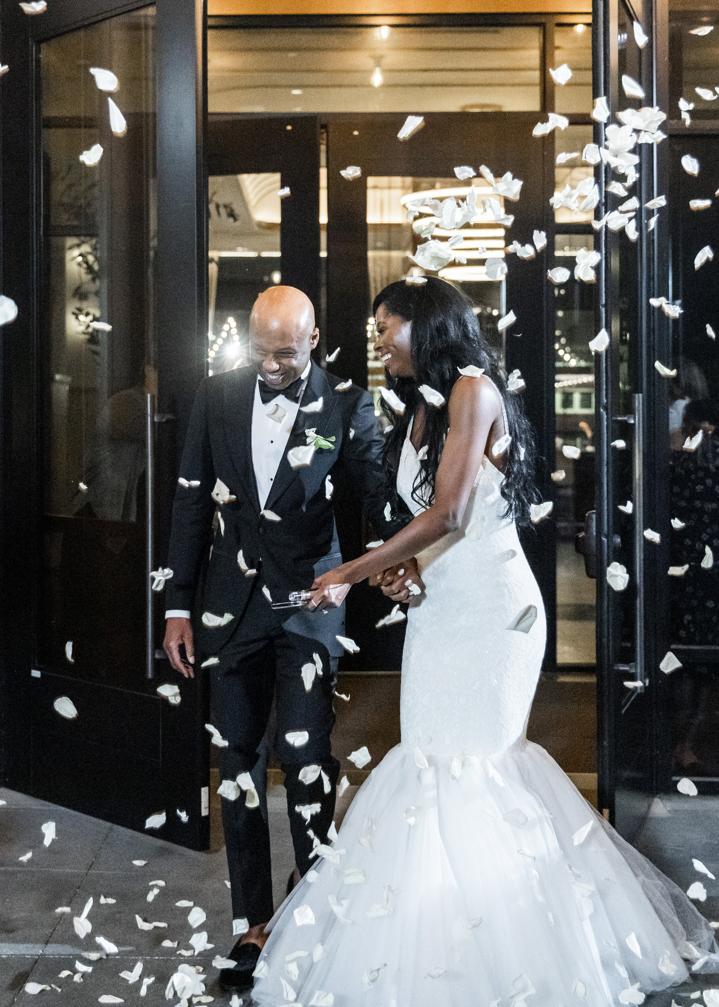  White flower petals shower a happy bride and groom as they exit their Dallas, Texas wedding venue. Wedding exit pictures ideas for wedding reception exit flower petal wedding exit white flower petals at a wedding hotel vin texas wedding fort worth w