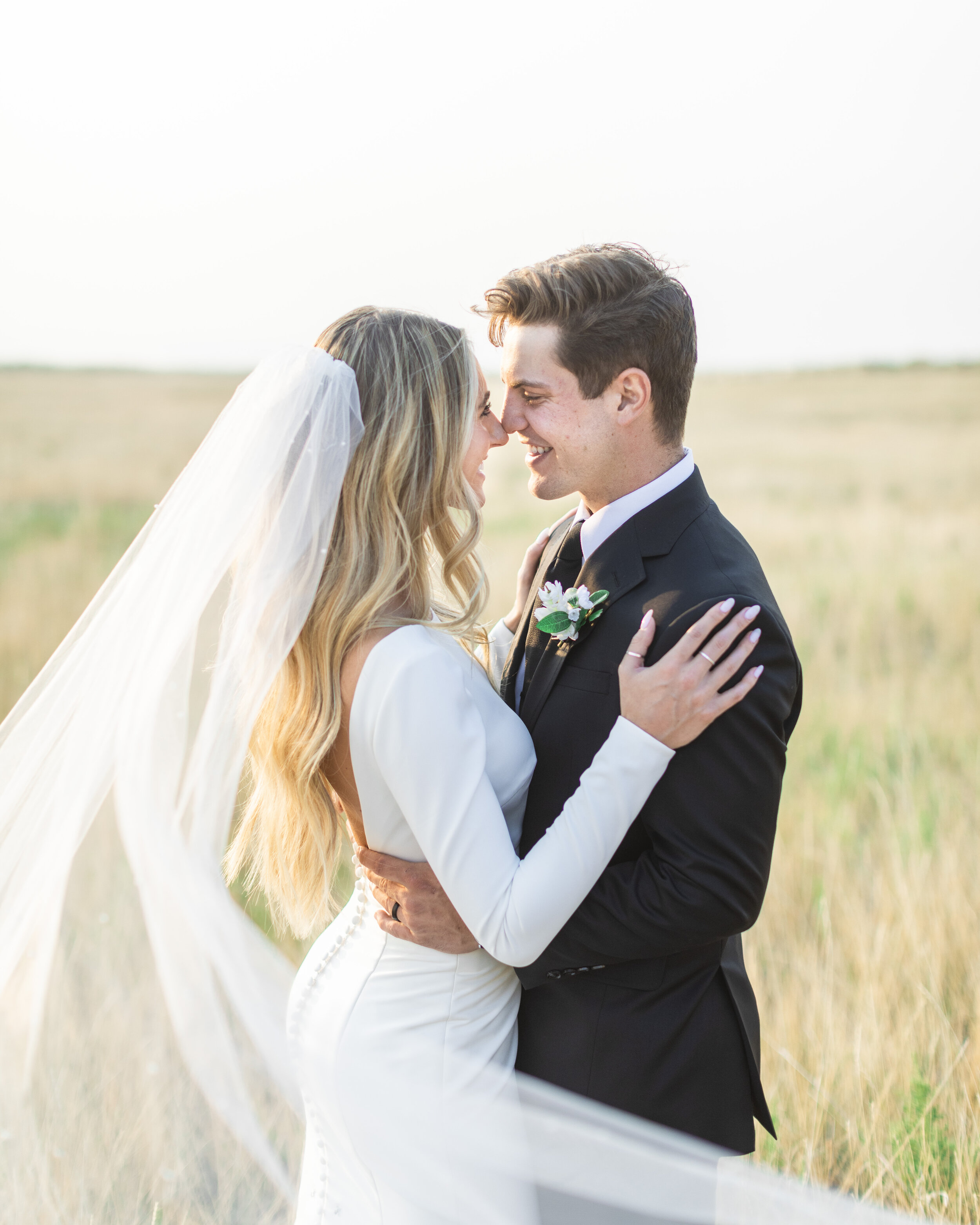  A newly wed couple touch noses at sunset with golden light by Savanna Richardson Photography a Salt Lake City Wedding Photographer. open back wedding dress with buttons down the back long blonde hair black tie #savannarichardsonphotography #savannaa