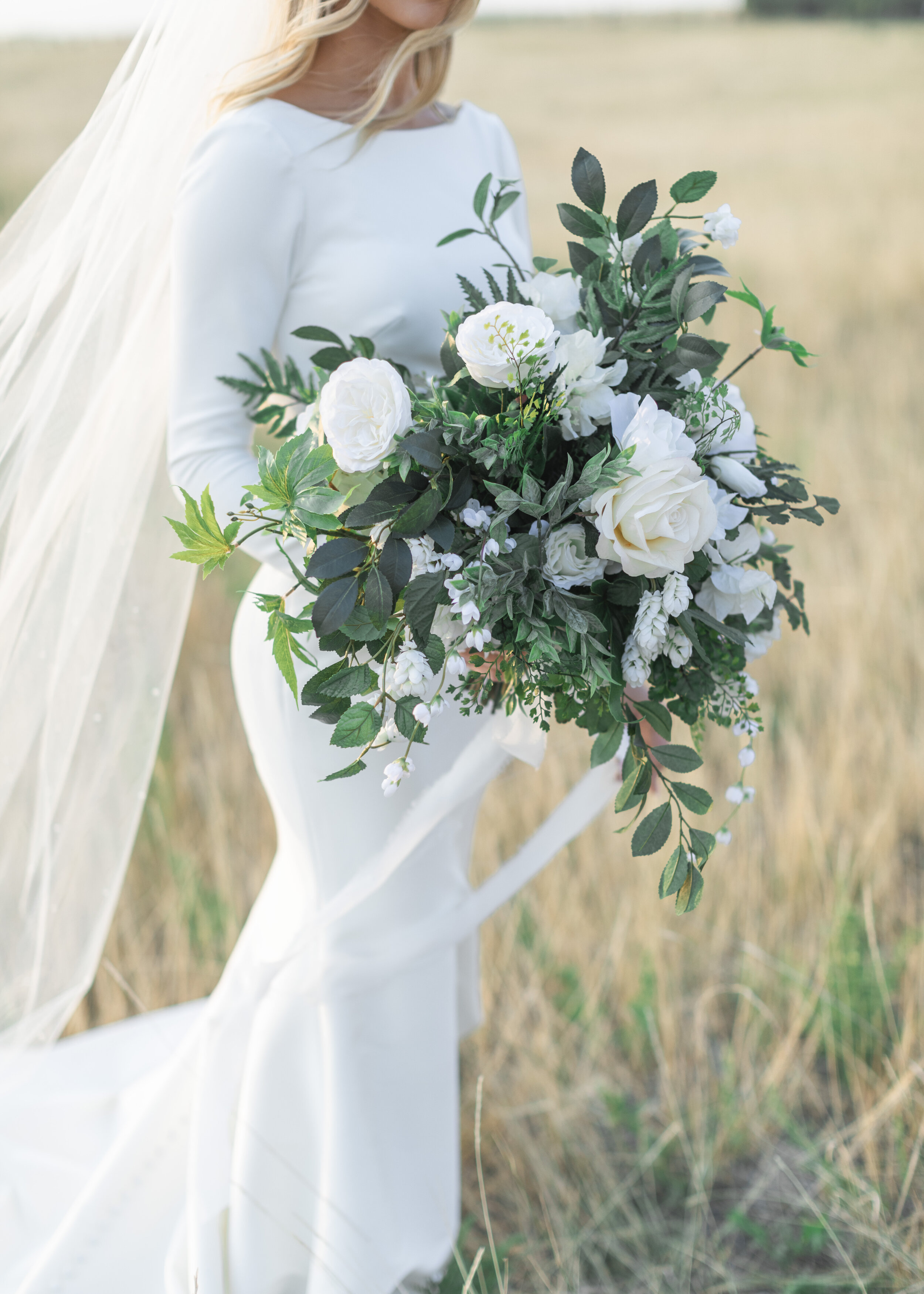  A beautiful bridal bouquet featuring large white flowers with lots of green foliage being held by the bride in a yellow grass field in Salt Lake City by Savana Richardson Photography. Bridal bouquet summer wedding bouquet white floral bouquet #savan