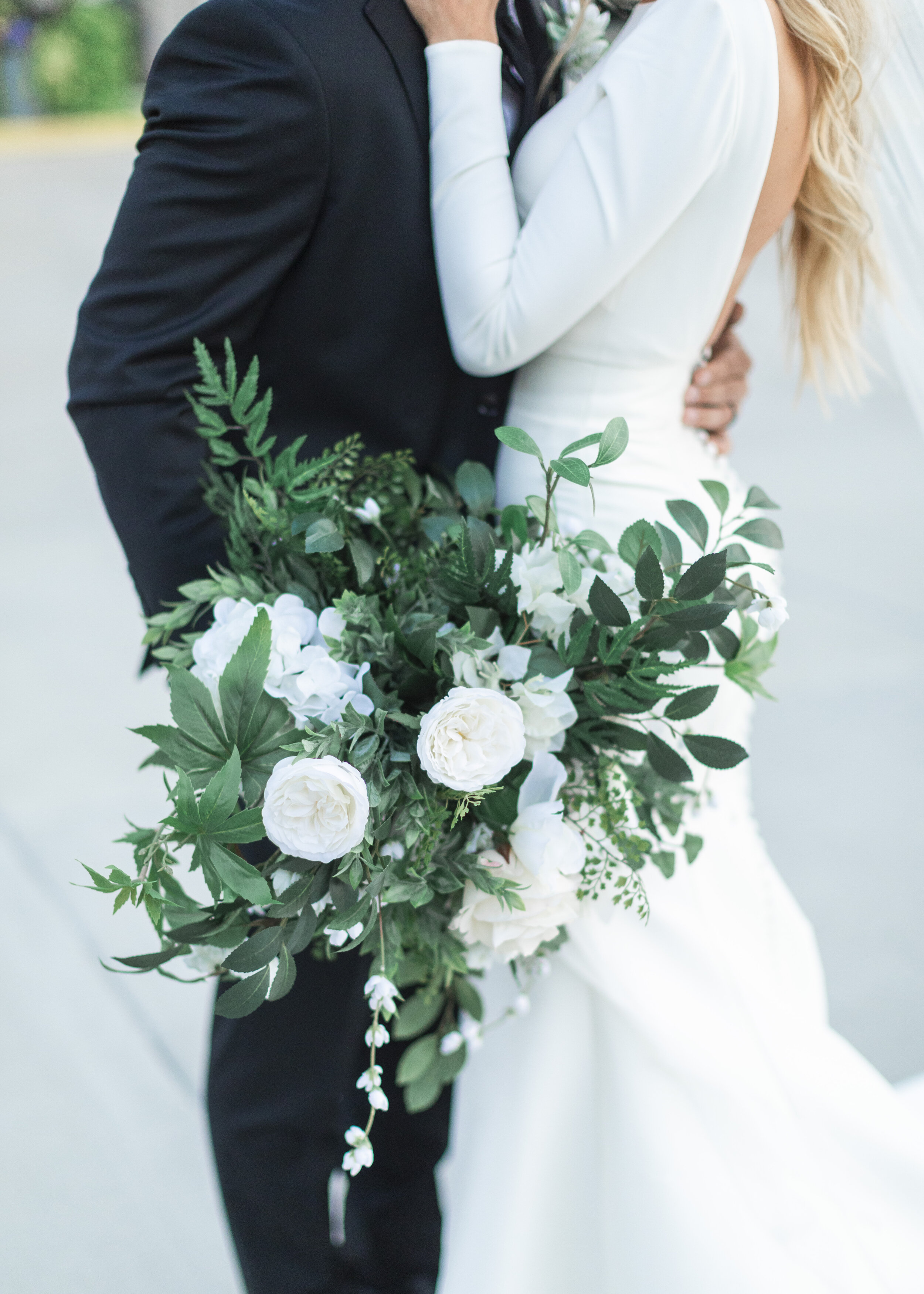  A newly married couple embrace while the groom holds a stunning white and green floral bouquet captured by Salt Lake City photographer Savanna Richardson Photography. Detailed wedding shot featuring bridal bouquet summer Utah weddings #savannarichar