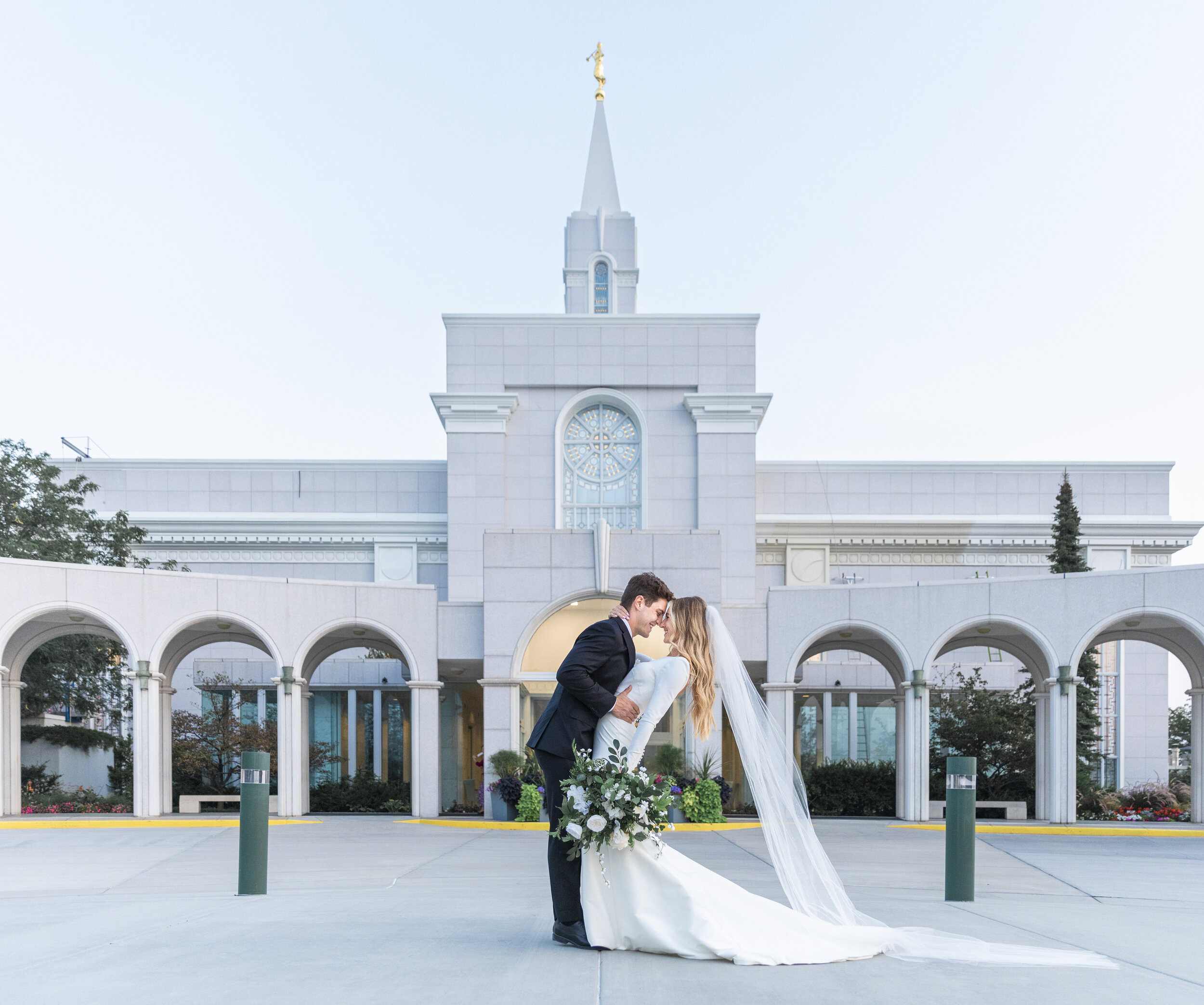  Breathtaking photo of a bride and groom going in for a kiss in front of the Bountiful Latter-Day Saint Temple captured by Savanna Richardson Photography. couple dip in front of LDS temple stunning temple wedding portraits #savannarichardsonphotograp