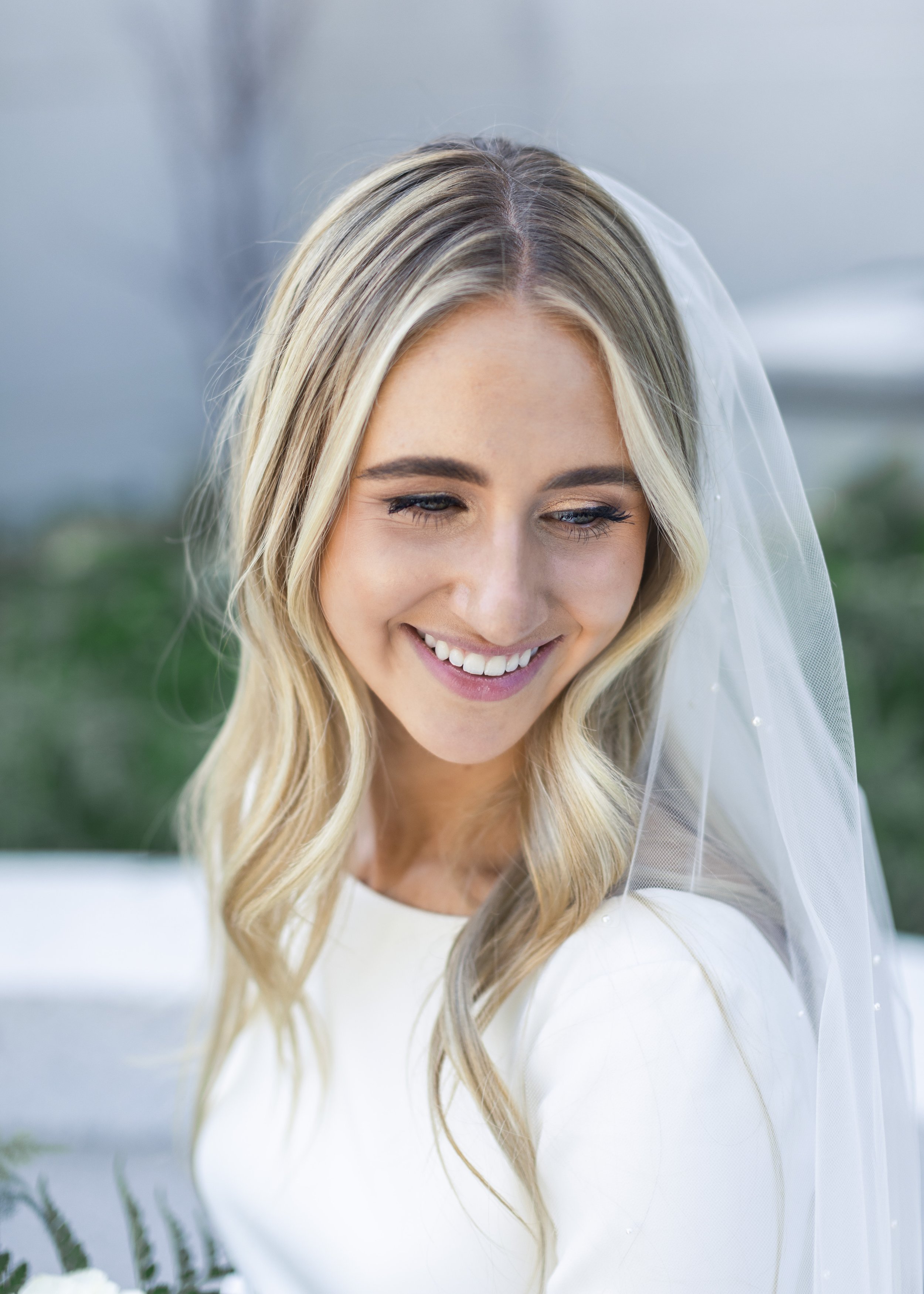  Bride with smooth white fitted wedding gown smiles brightly with her hair flowing down her shoulders in Northern Utah by Savanna Richardson Photography. bride with hair down simple wedding dress #savannaricharsonphotography #savannarichardsonwedding