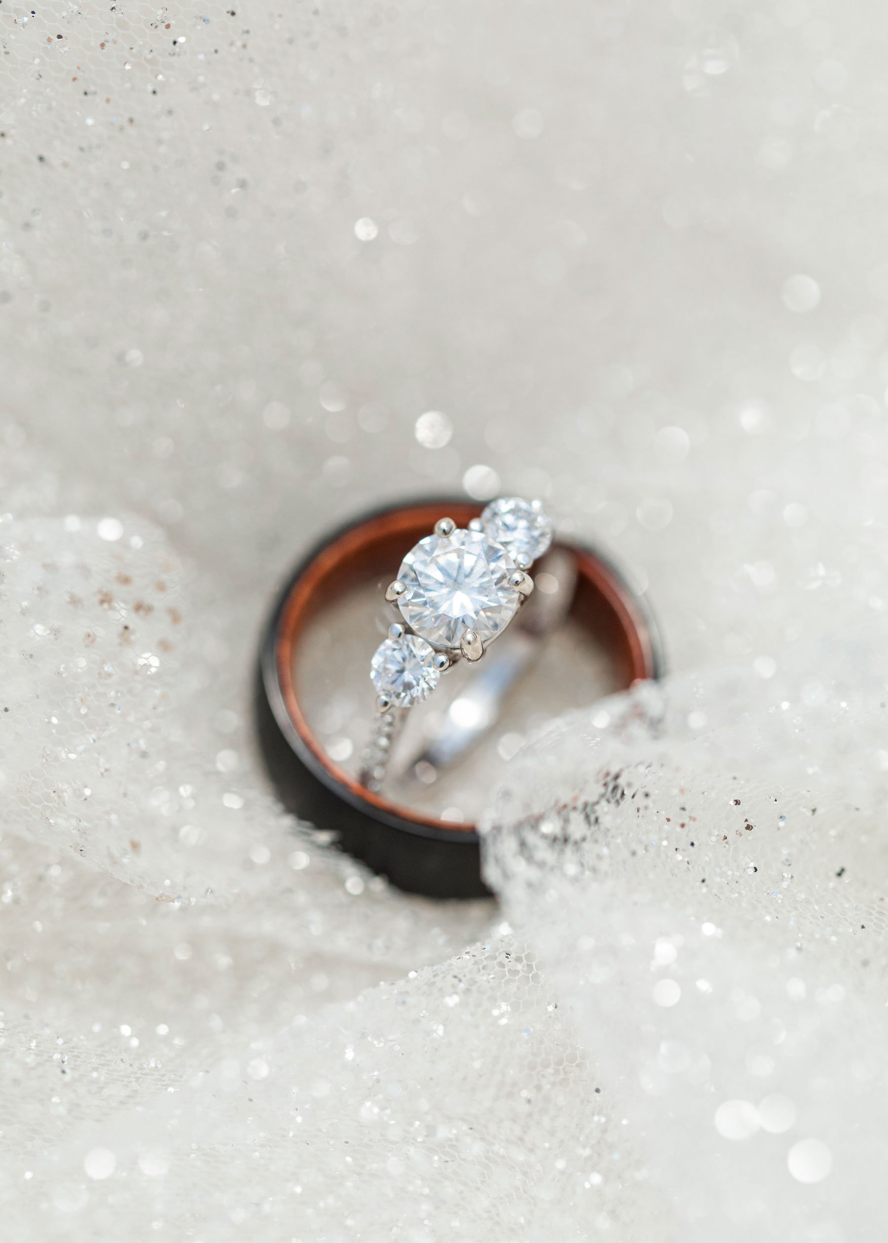  Black and wood groom ring with a three-round diamond wedding ring photo laying on the sparkly bridal gown by Savanna Richardson Photography during a Utah County Wedding. ring shot wedding ring silver wedding ring #savannarichardsonphotography #Savan