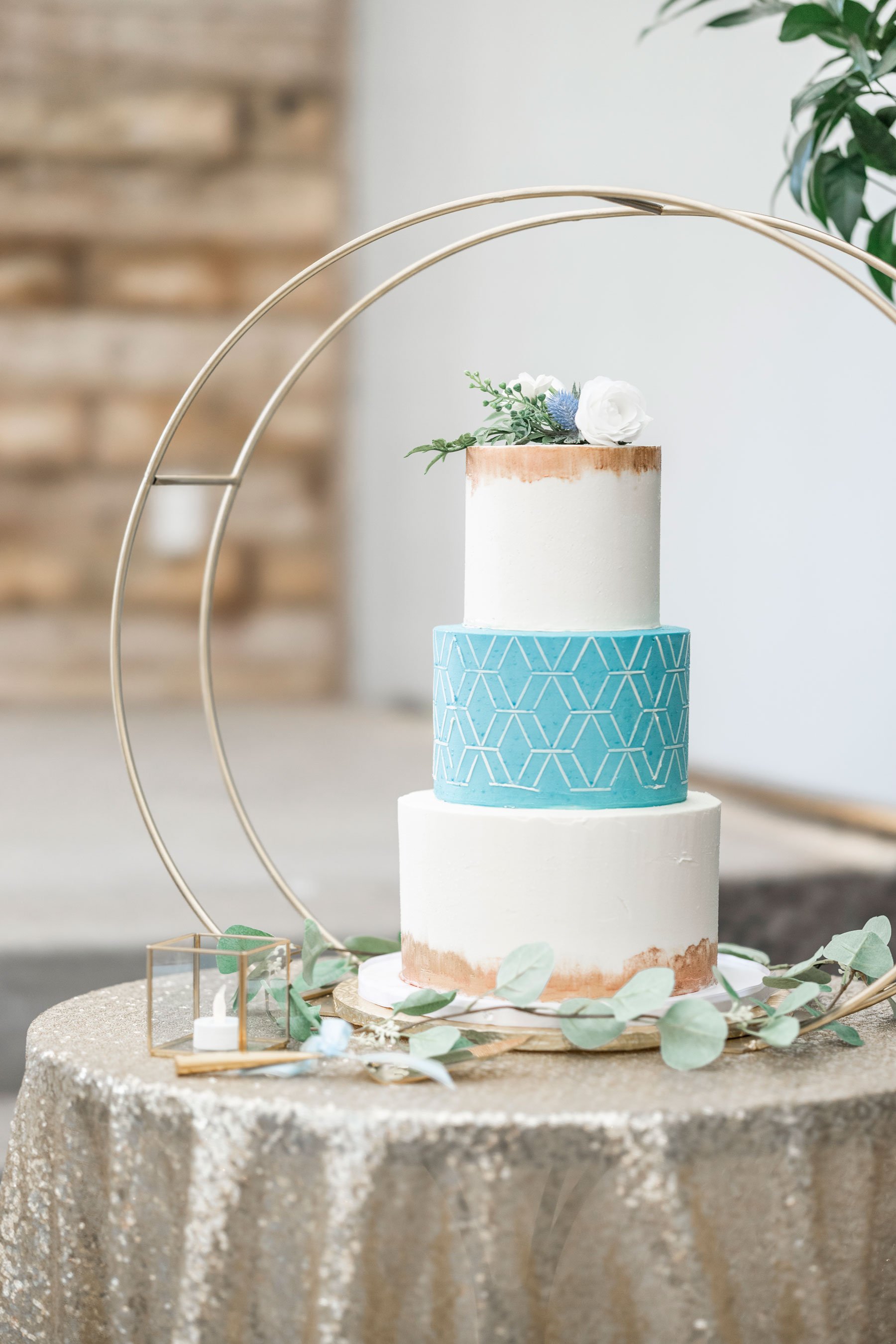  Stunning three-tier blue buttercream wedding cake on a sparkly gold tablecloth and a gold ring around it photo taken by Savanna Richardson Photography at an Orem wedding. Shade and Home Garden Center blue wedding cake three-tier wedding cake gold ac