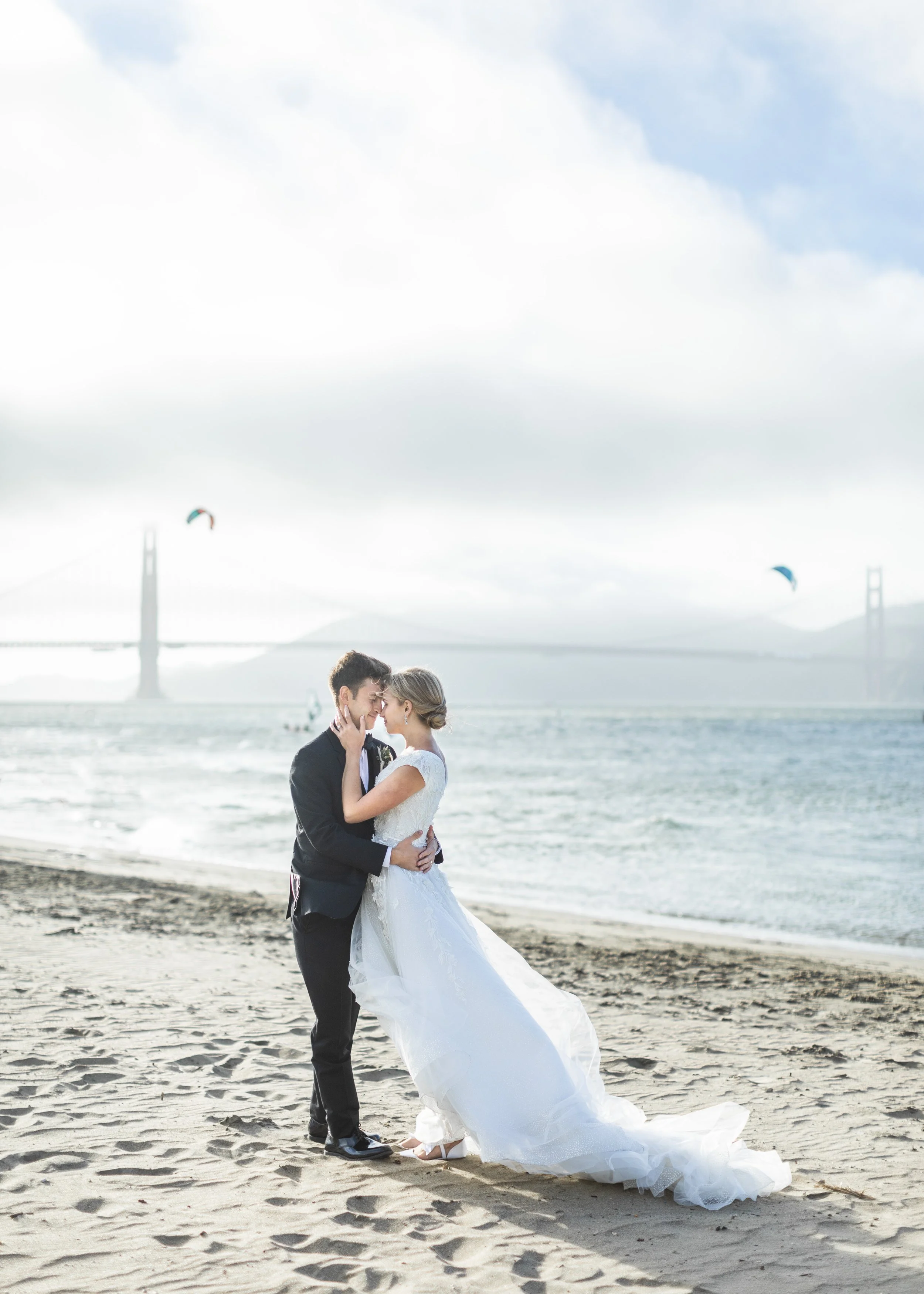  A bridal kissing pic on a beach with a bridge in the background with Savanna Richardson Photography. beach bridals beach with ocean and bridge wedding pics #savannarichardsonphotography #utahphotographers #slcweddings #utahcountyweddingphotographer 