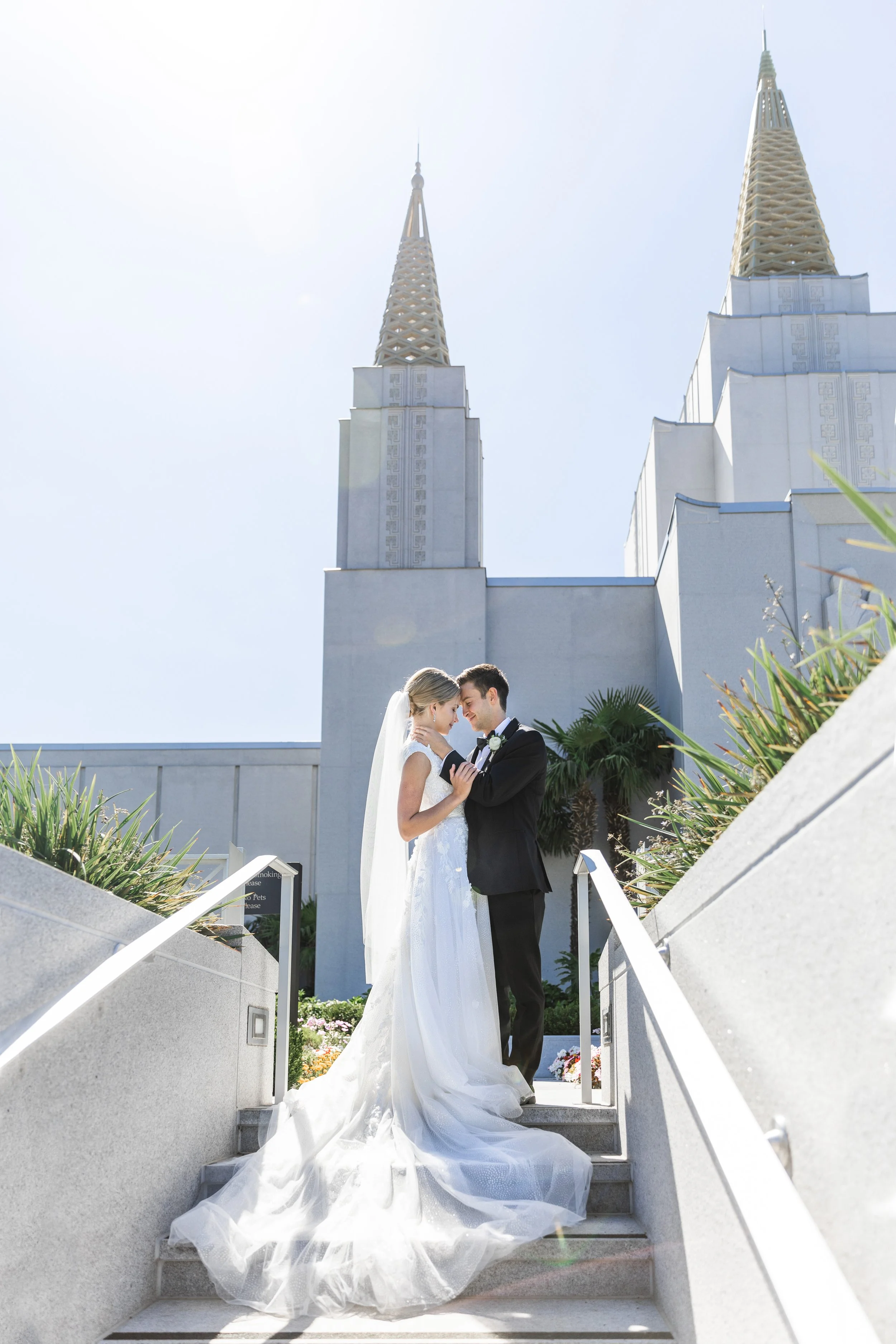  A newly married couple stand on stairs in front of LDS temple by Savanna Richardson Photography. professional wedding photographer LDS temple wedding #savannarichardsonphotography #utahphotographers #slcweddings #utahcountyweddingphotographer 