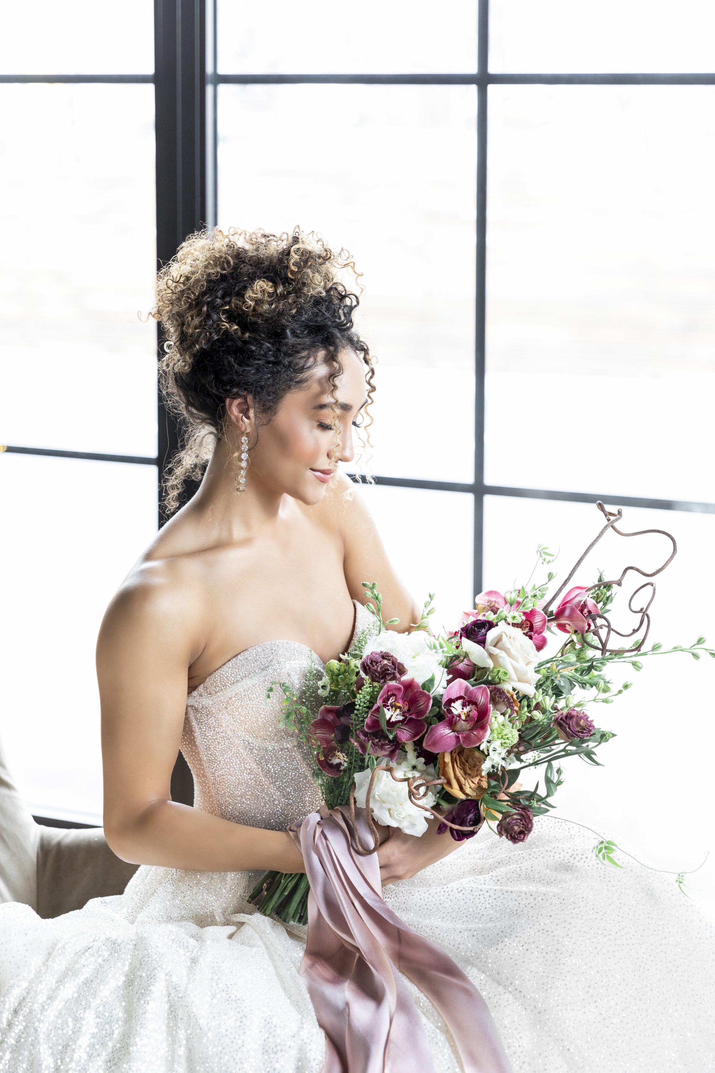  Bride in a strapless wedding gown holds a purple bouquet next to a bright light window by Savanna Richardson Photography. summer purple bouquet #savannarichardsonphotography #utahvendor #utahweddingphotographer #MilleFleurDesign #Utahweddingdesigns 