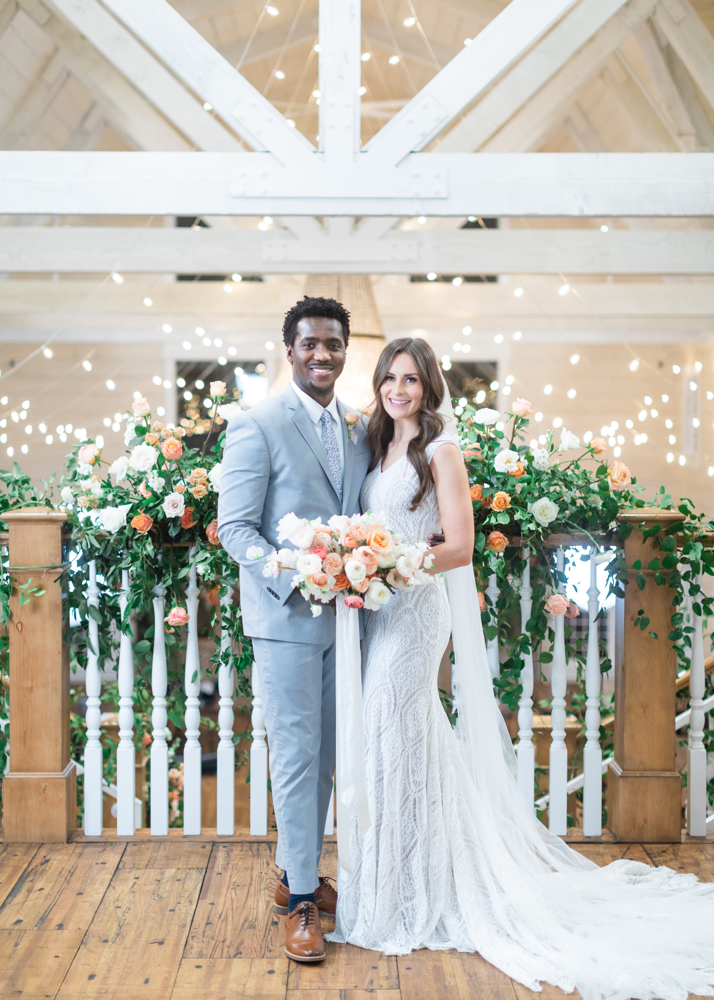  Bride with lace wedding gown and groom in gray suit holding the bridal bouquet together captured by Savanna Richardson Photography. peach bouquet #savannarichardsonphotography #utahvendor #utahweddingphotographer #MilleFleurDesign #Utahweddingdesign