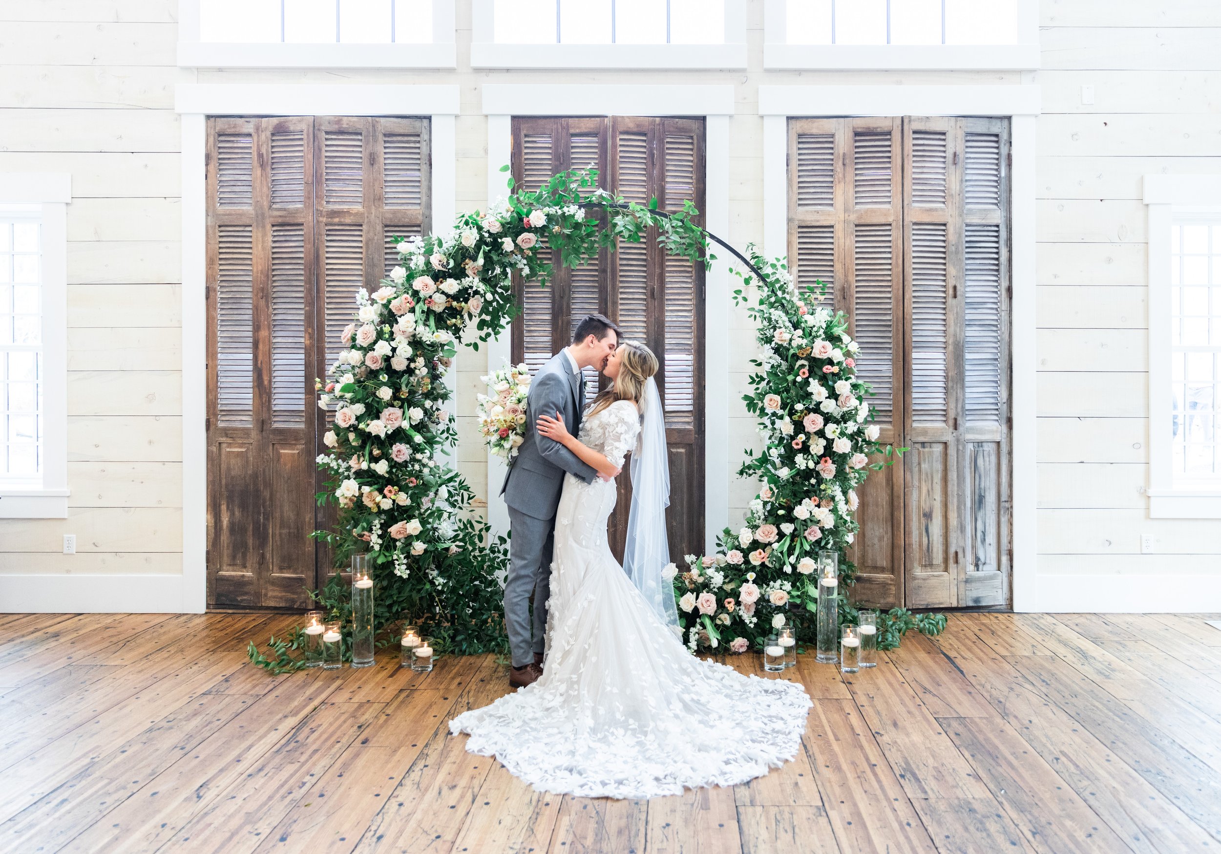  Utah wedding photographer Savanna Richardson Photography captures a couple kissing in front of a round floral altar. circle altars floral design #savannarichardsonphotography #utahvendor #utahweddingphotographer #MilleFleurDesign #Utahweddingdesigns