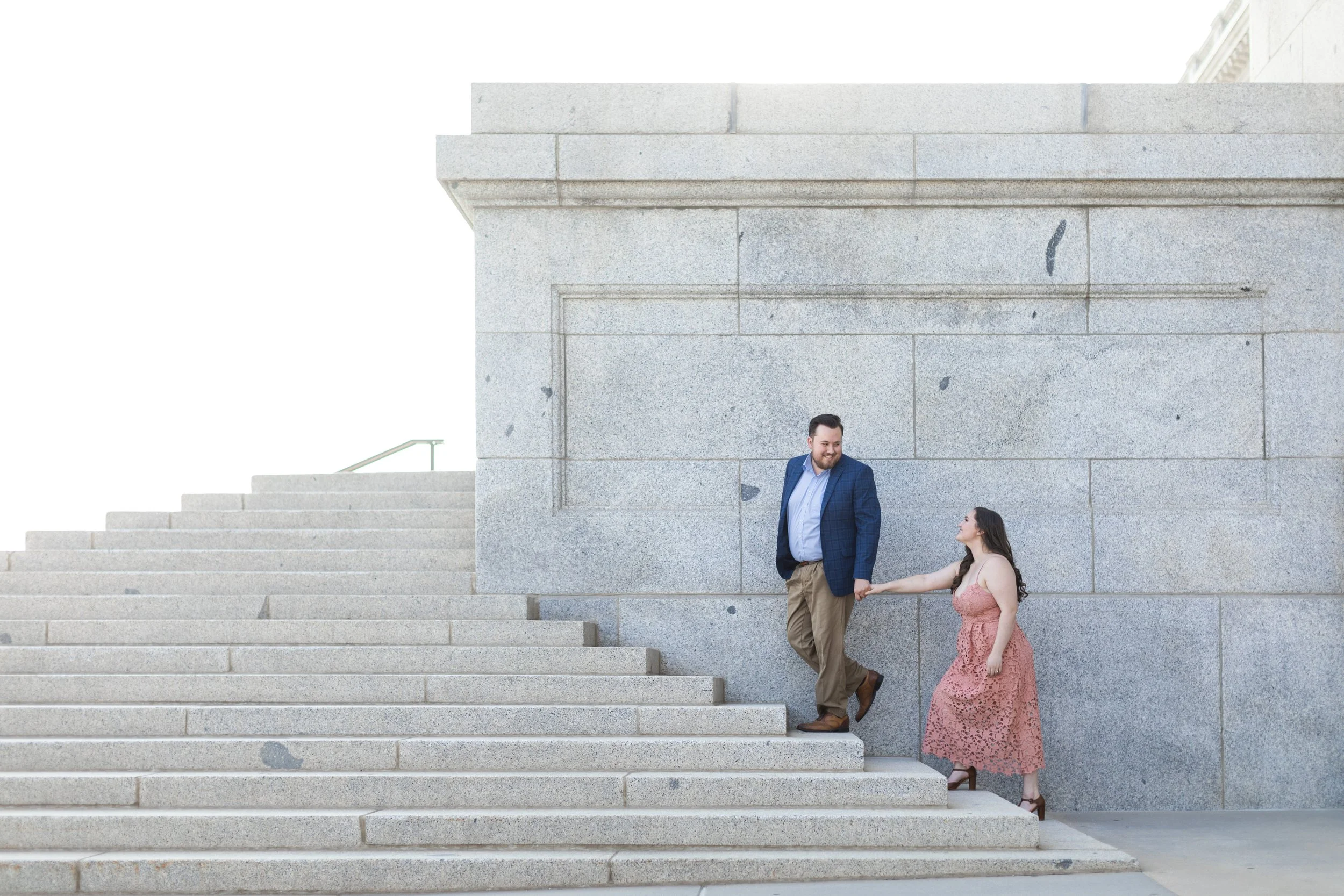  At the Utah Capitol, a man leads a woman up a granite staircase by Savanna Richardson Photography. Utah capitol engagement shots summer engagement #savannarichardsonphotography #Utahcapitolphotography #utahengagements #utahengagementphotographer 