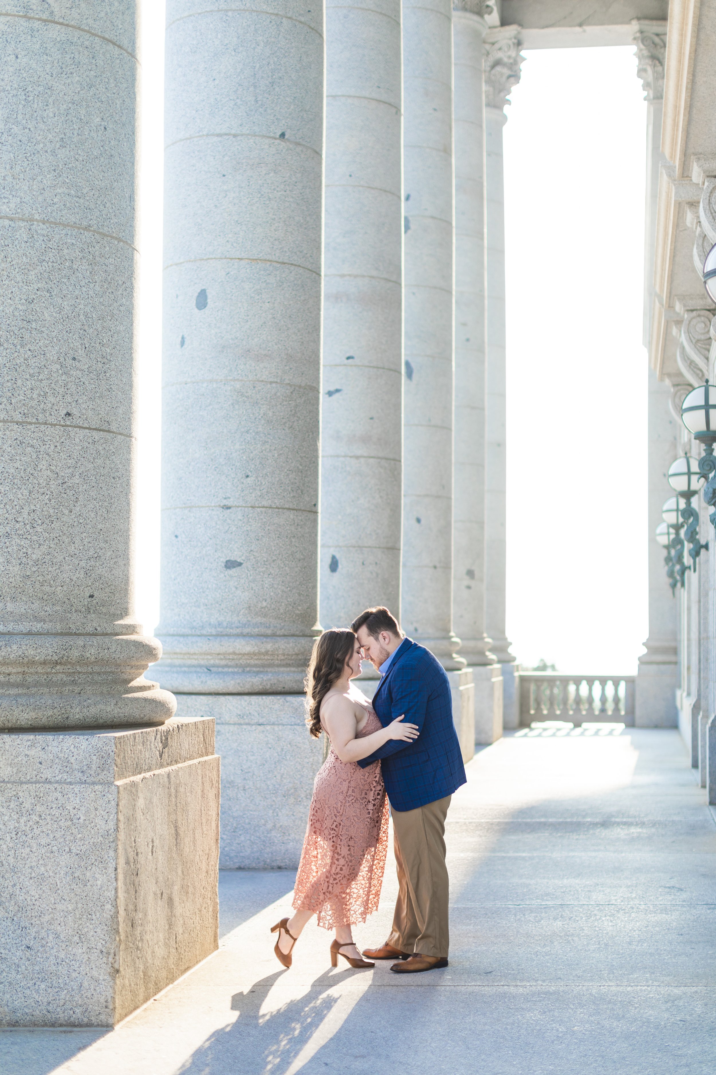  Next to granite pillars at the Utah State Capitol a newly engaged couple kisses by Savanna Richardson Photography. northern Utah photographers #savannarichardsonphotography #Utahcapitolphotography #utahengagements #utahengagementphotographer 
