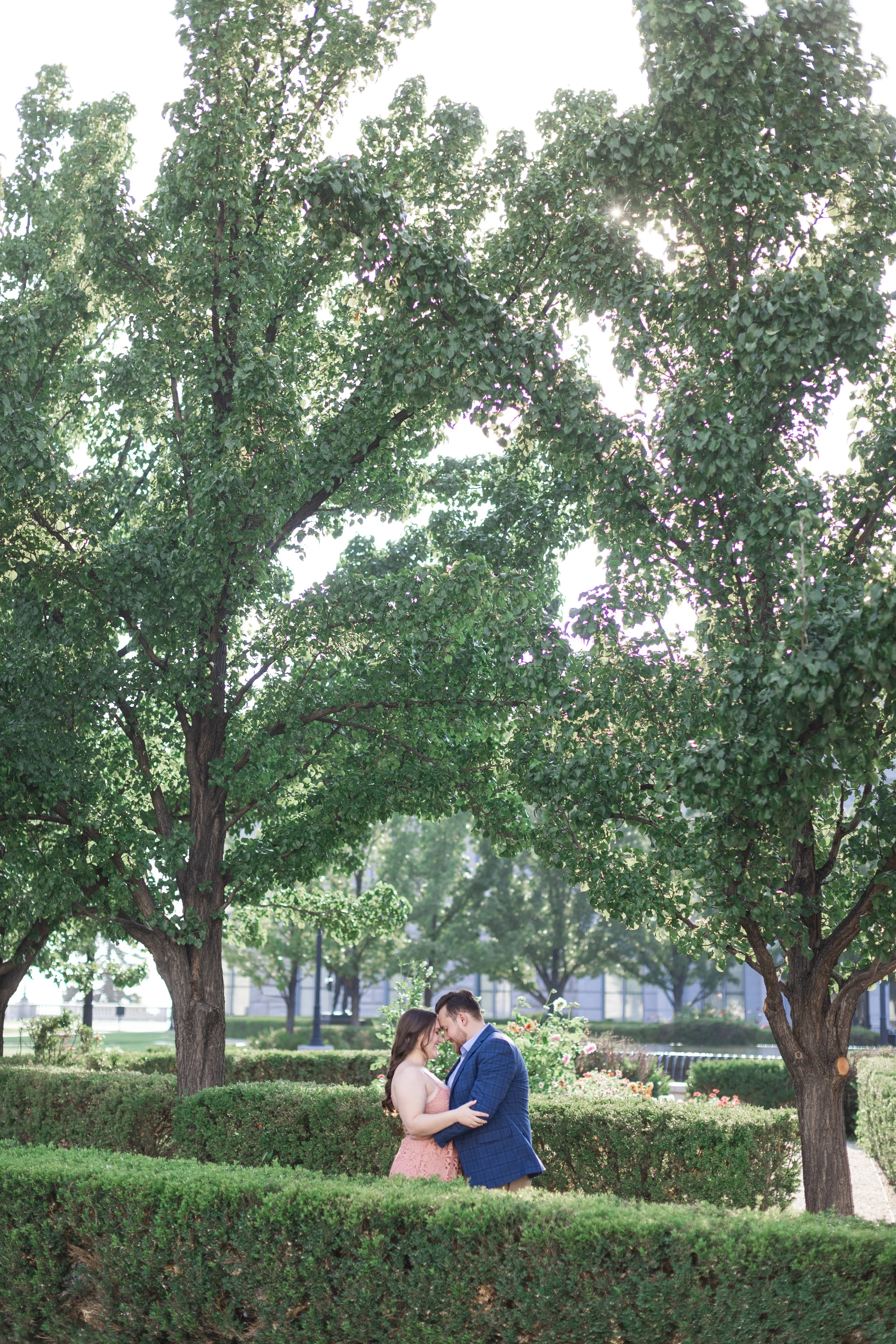  Under beautiful green summer trees, fiances kiss by Savanna Richardson Photography a Utah photographer. State Capitol engagements wed announcement pics #savannarichardsonphotography #Utahcapitolphotography #utahengagements #utahengagementphotographe