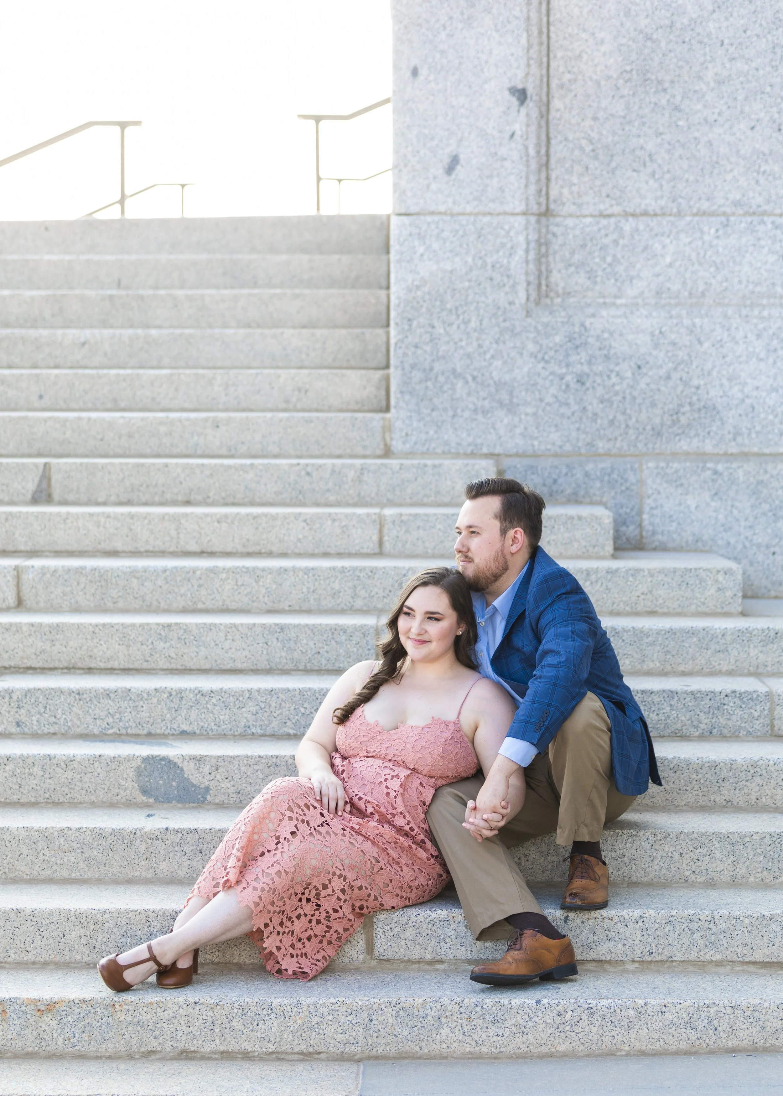  Engaged couple snuggles while sitting on the Capitol stair in SLC Utah by Savanna Richardson Photography. couple stair portraits couple outfit ideas #savannarichardsonphotography #Utahcapitolphotography #utahengagements #utahengagementphotographer 