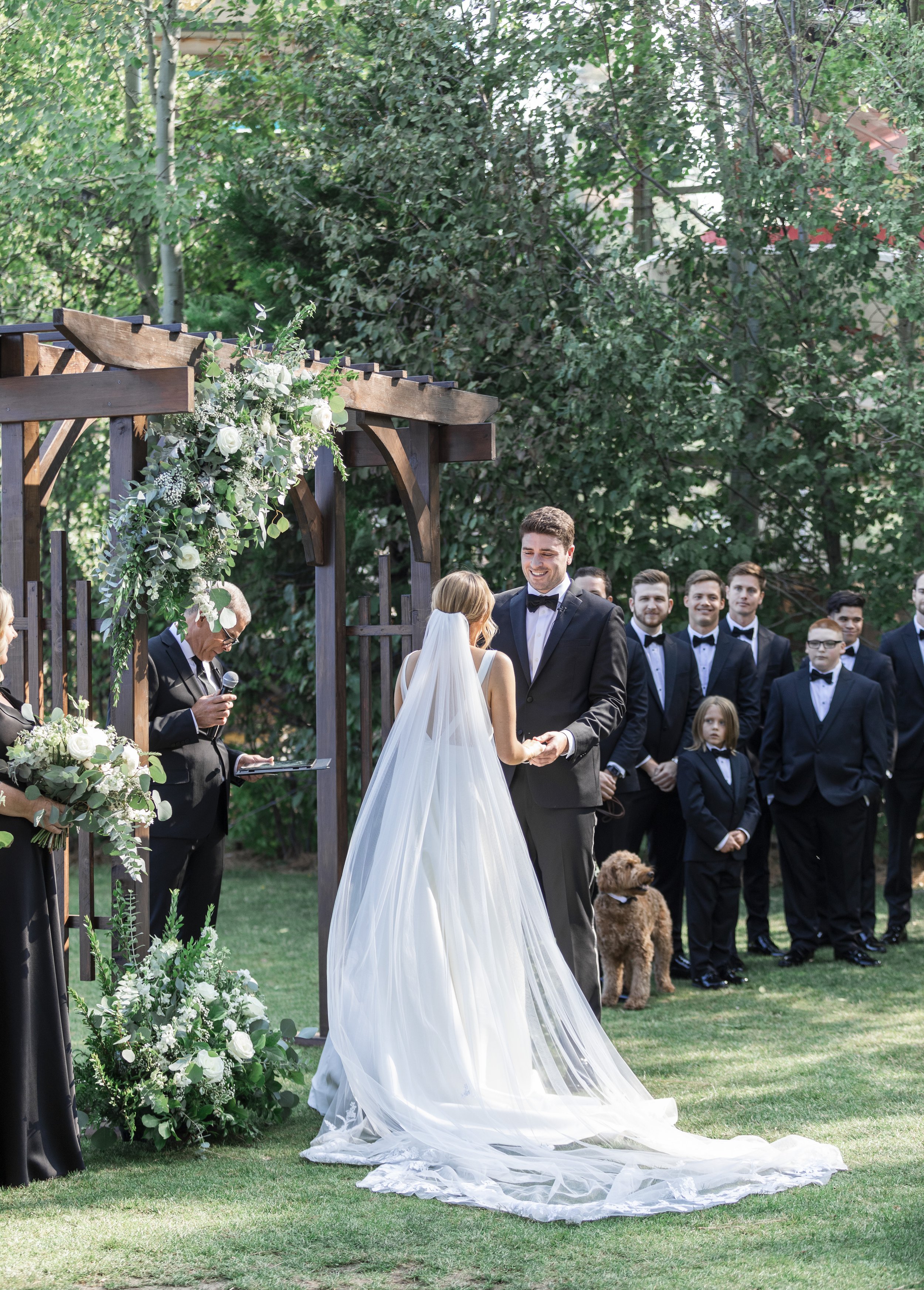  A bride and groom holding hands at a wooden altar during an outdoor wedding captured by Savanna Richardson Photography. outdoor altar summer wed #savannarichardsonphotography #tahoewedding #lakesidewedding #outdoorwedding #summerwedding #laketahoe 