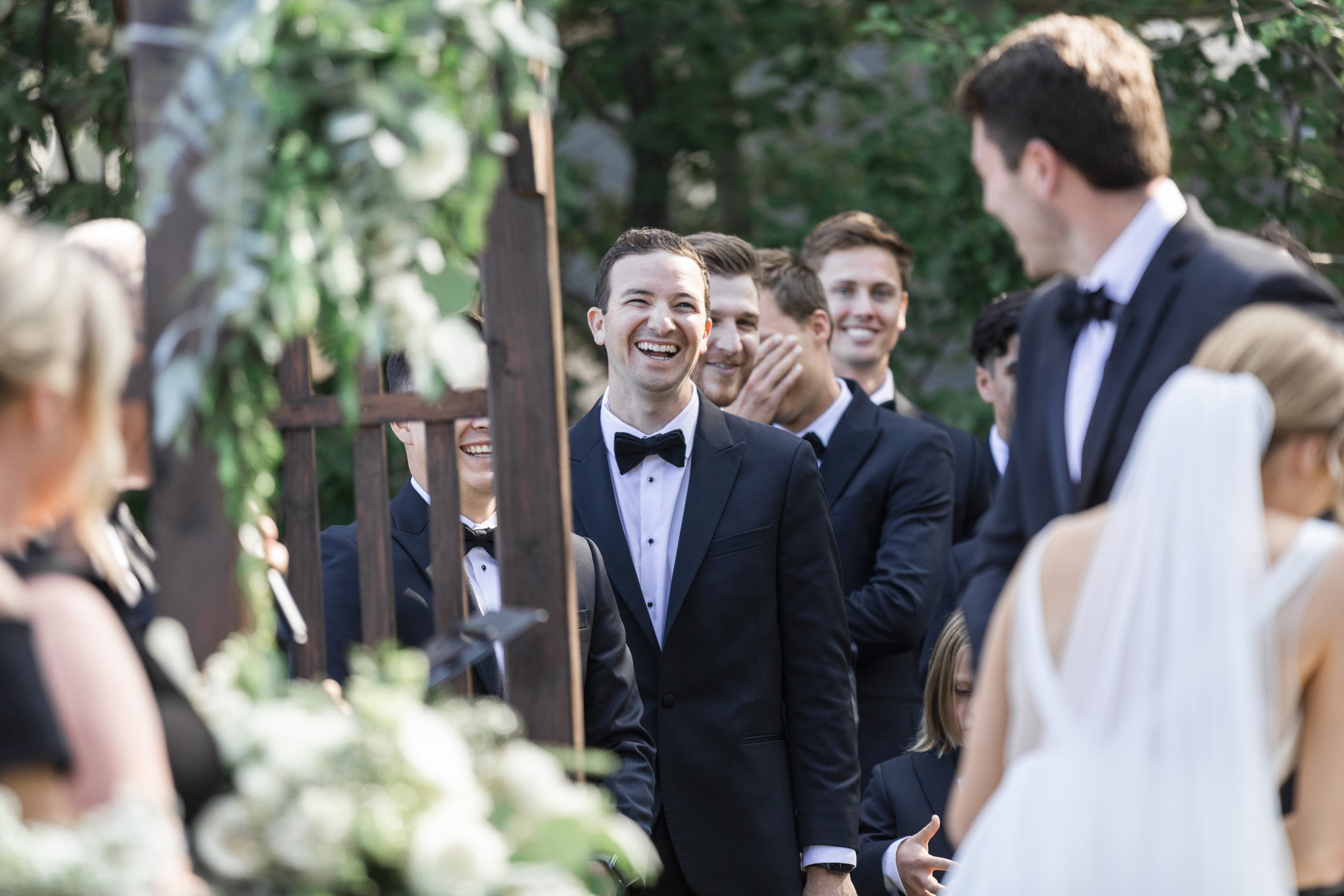  During a lakeside wedding, Savanna Richardson Photography captures the groomsmen laughing during the ceremony. groomsmen candids wedding near water #savannarichardsonphotography #tahoewedding #lakesidewedding #outdoorwedding #summerwedding #laketaho