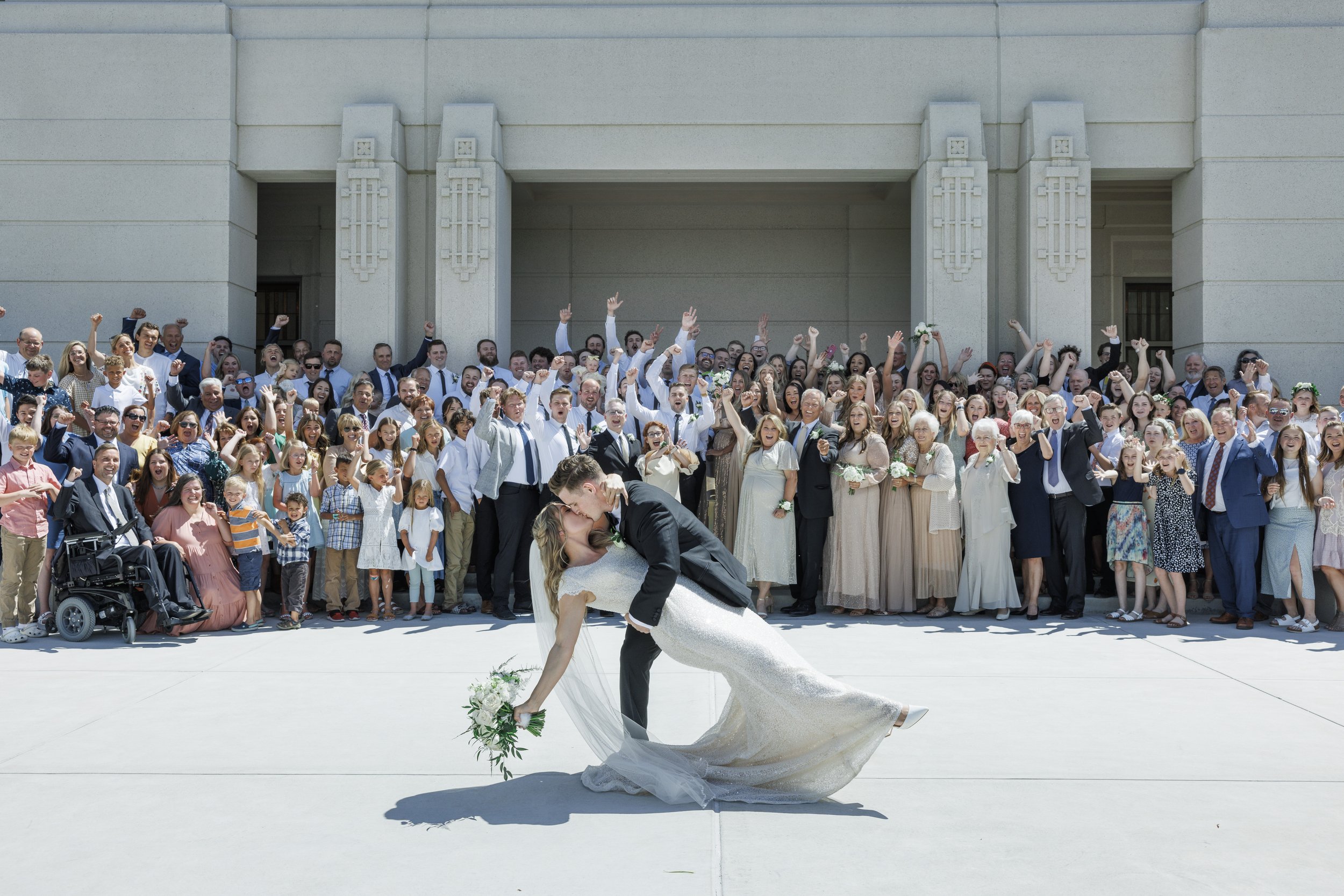  Groom dipping his new wife for a kiss in front of the Meridian, Idaho LDS Temple surrounded by loved ones. #tonygrove #cachevalley #utahbride #ldstemplewedding #savannarichardsonphotography #utahweddingphotographer #summerwedding #outdoorreception 