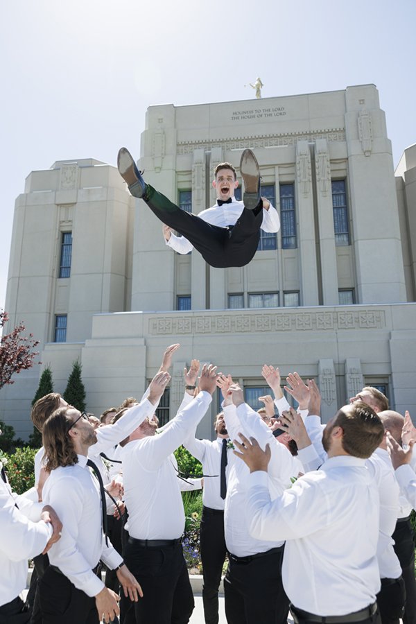 Groomsmen toss the excited groom up in the air in front of the Meridian Idaho LDS Temple during a summer wedding. #savannarichardsonphotography #cachevalleyweddingphotographer #weddingposeinspo #groomsmen #ldstemplewedding #meridianidaho #funposeide