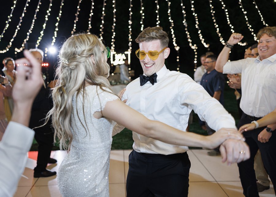  Groom smiling and wearing sunglasses while dancing with his new wife at the outdoor wedding reception at Tony Grove in Cache Valley. #savannarichardsonphotography #weddingreceptioninspo #outdoorwedding #tonygrove #cachevalley #utahweddingphotographe