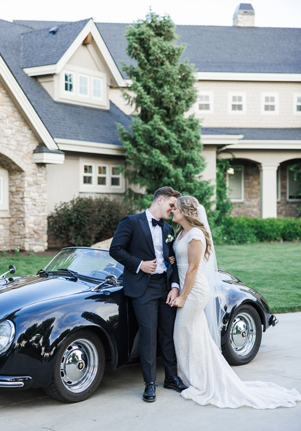  Groom and bride going in for a kiss outside their Tony Grove wedding reception in front of a classic Porsche they will use as they exit their wedding later that evening. #tonygrove #summerwedding #classiccar #kissingpose #savannarichardsonphotograph