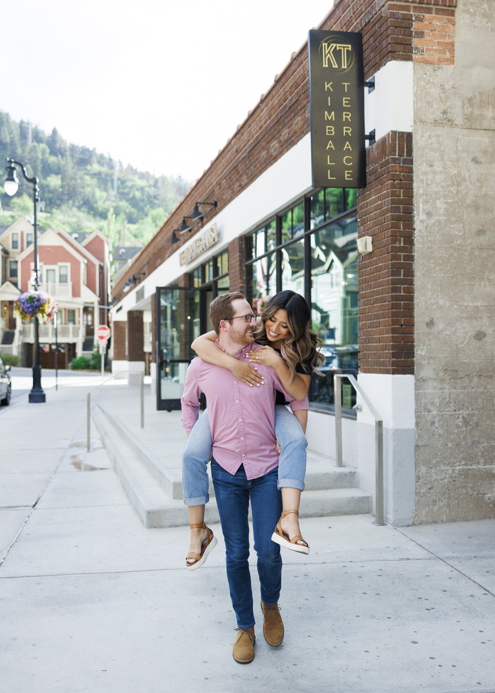  A man in a pink button-up gives his fiance a piggyback ride in Park City by Savanna Richardson Photography. city engagements Utah high end #ParkCityEngagements #ParkCityPhotographers #SavannaRichardsonPhotography #SavannaRichardsonEngagements 